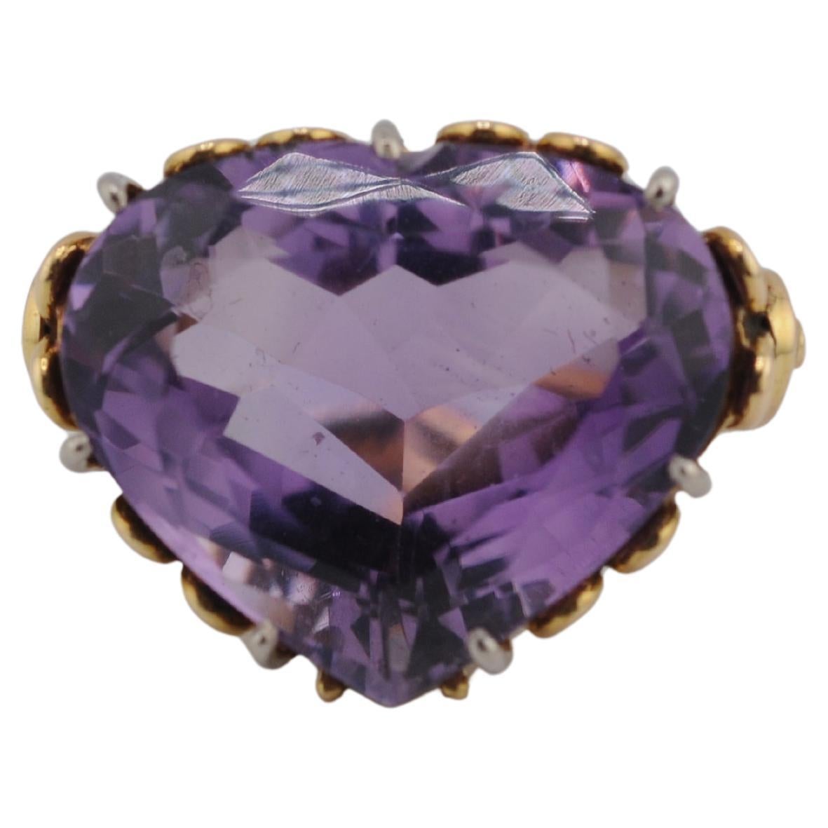 Cette bague audacieuse et accrocheuse en or jaune 14 carats est ornée d'une améthyste de 20 carats environ, taillée en cœur et richement colorée. L'améthyste est originaire du Brésil et présente une teinte violette vibrante et une grande