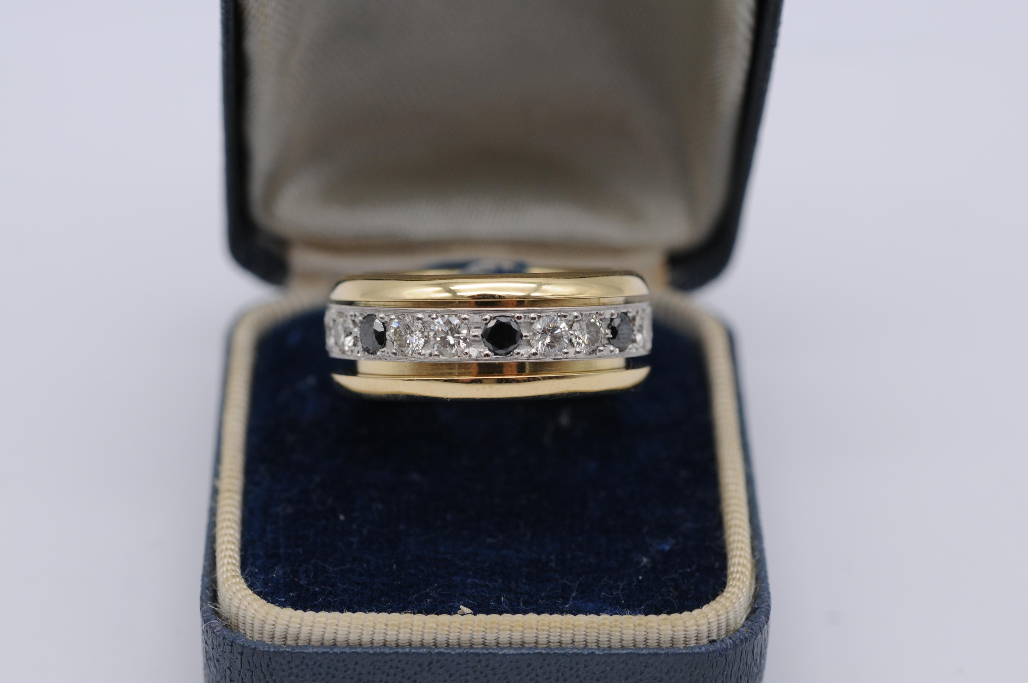 A stunning 18k yellow gold ring featuring a movable white gold memory band adorned with seven black brilliant-cut diamonds and 14 white brilliant-cut diamonds of exceptional quality. The unique feature of this piece is the rotatable white gold band,