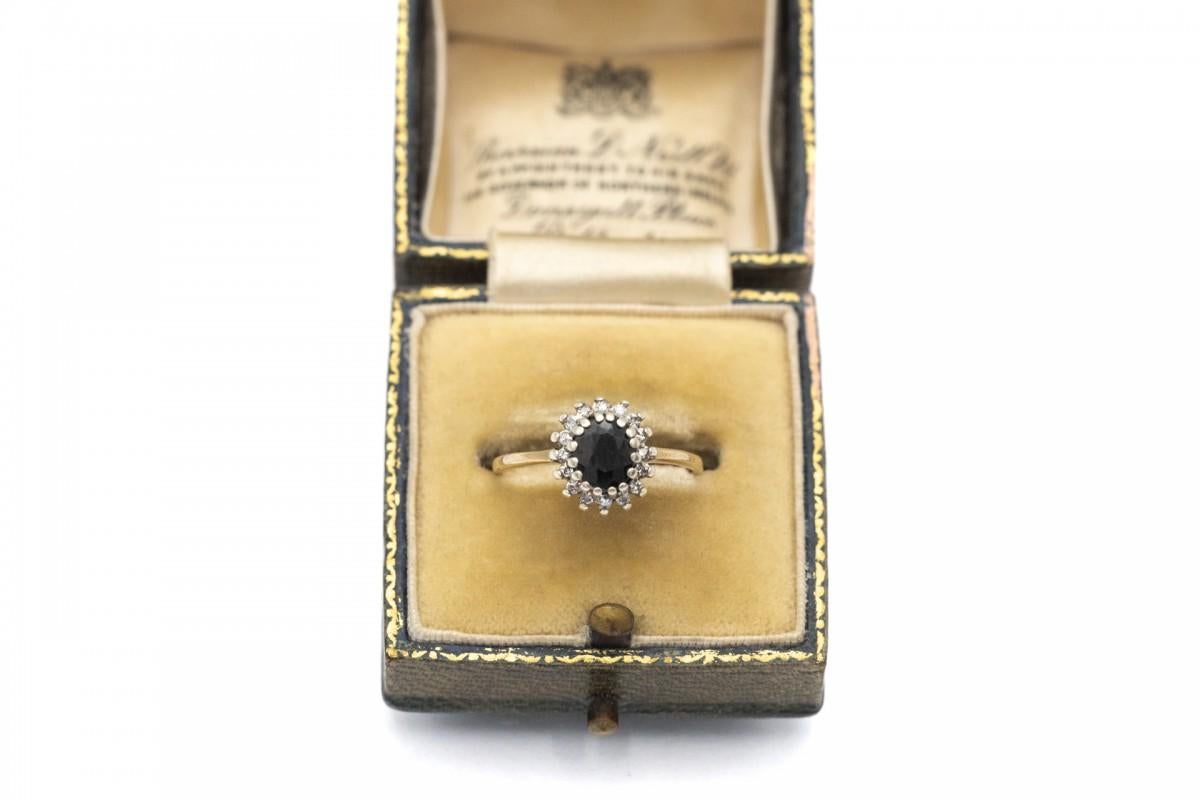 Anello d'oro antico in oro giallo 9 carati (finezza 375) ed elementi in argento. Decorato con uno zaffiro ovale centrale del peso di circa 1,00 ct, di colore blu scuro. Inoltre, è decorato con 16 diamanti taglio 8/8 del peso di 0,08 carati, colore