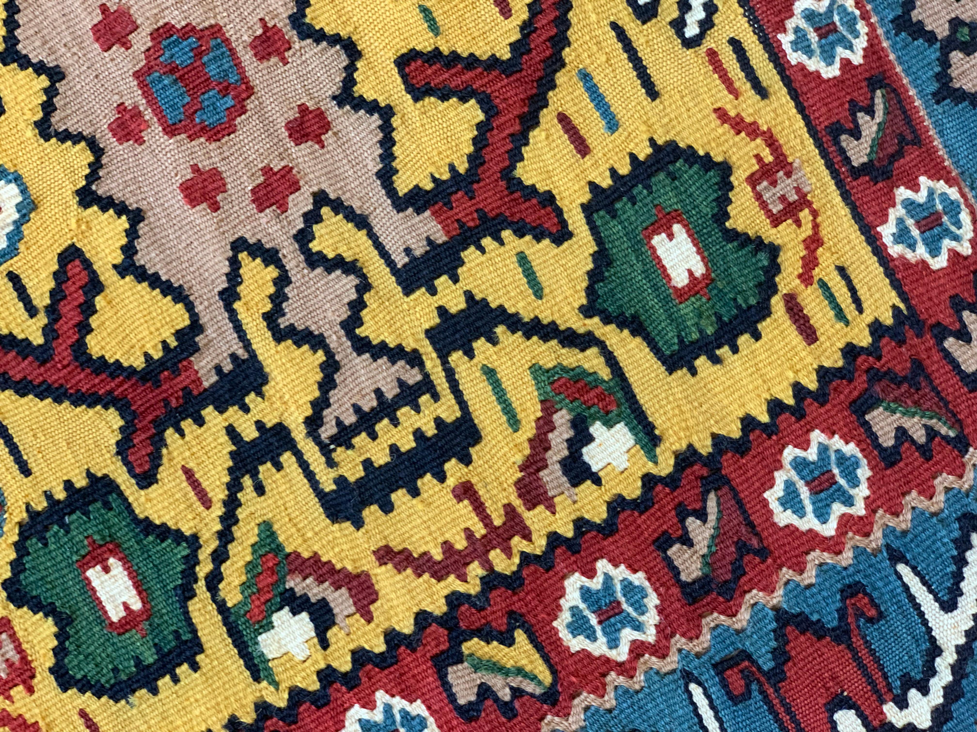 These two bold area rugs are handmade Kurdish Kilim rugs woven in the early 21st century, circa 2010. The design features a bold yellow background that has been decorated with accents of red, blue, ivory, and beige accents that make up the