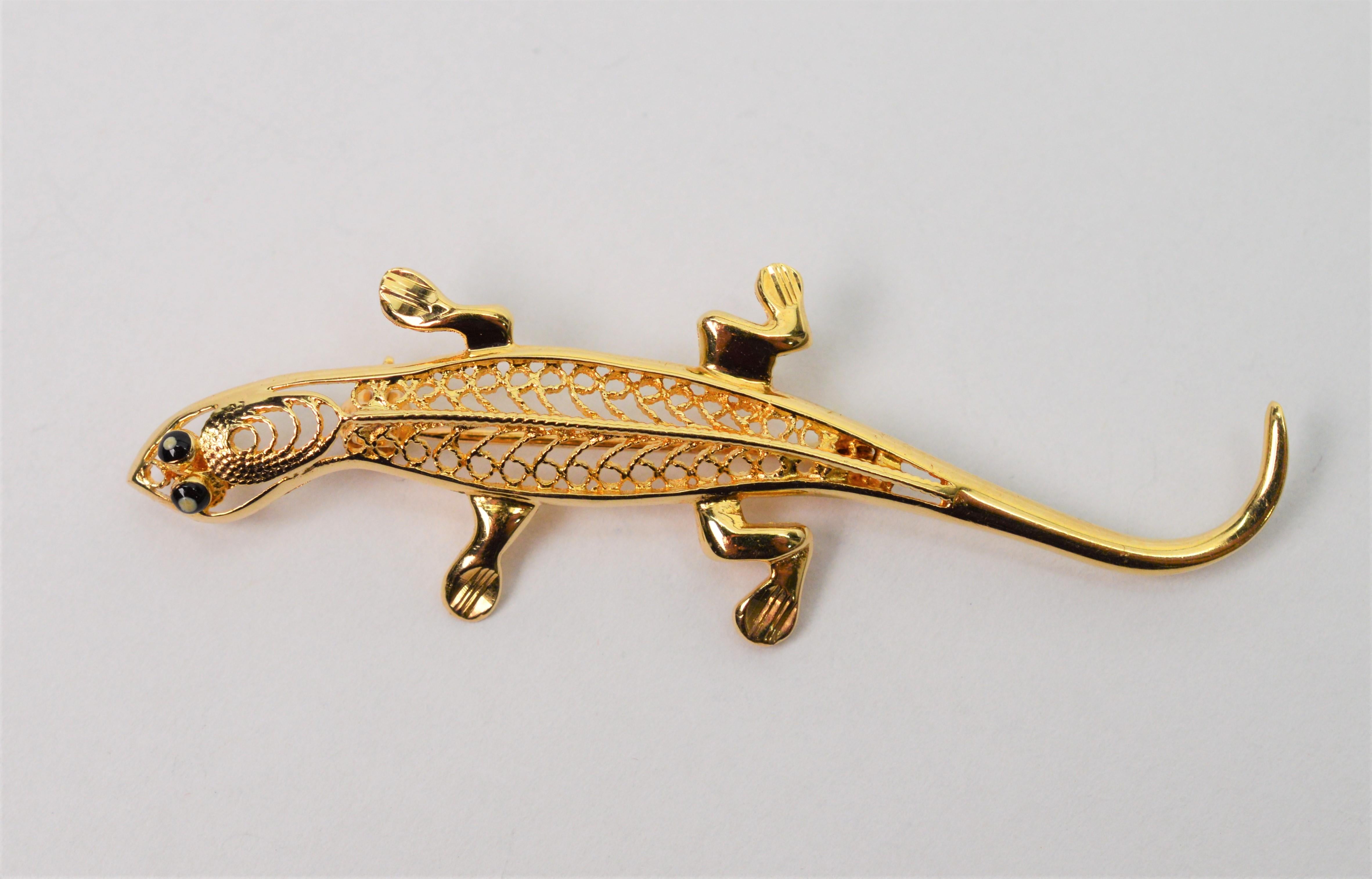 Accent your lapel with this adorable salamander, a symbol of rebirth. Crafted in fourteen karat yellow gold filigree with tiny onyx eyes, this little amphibian measures approximately 2-1/4 inches long by 3/4 inch wide. Stamped 14K by maker. Gift