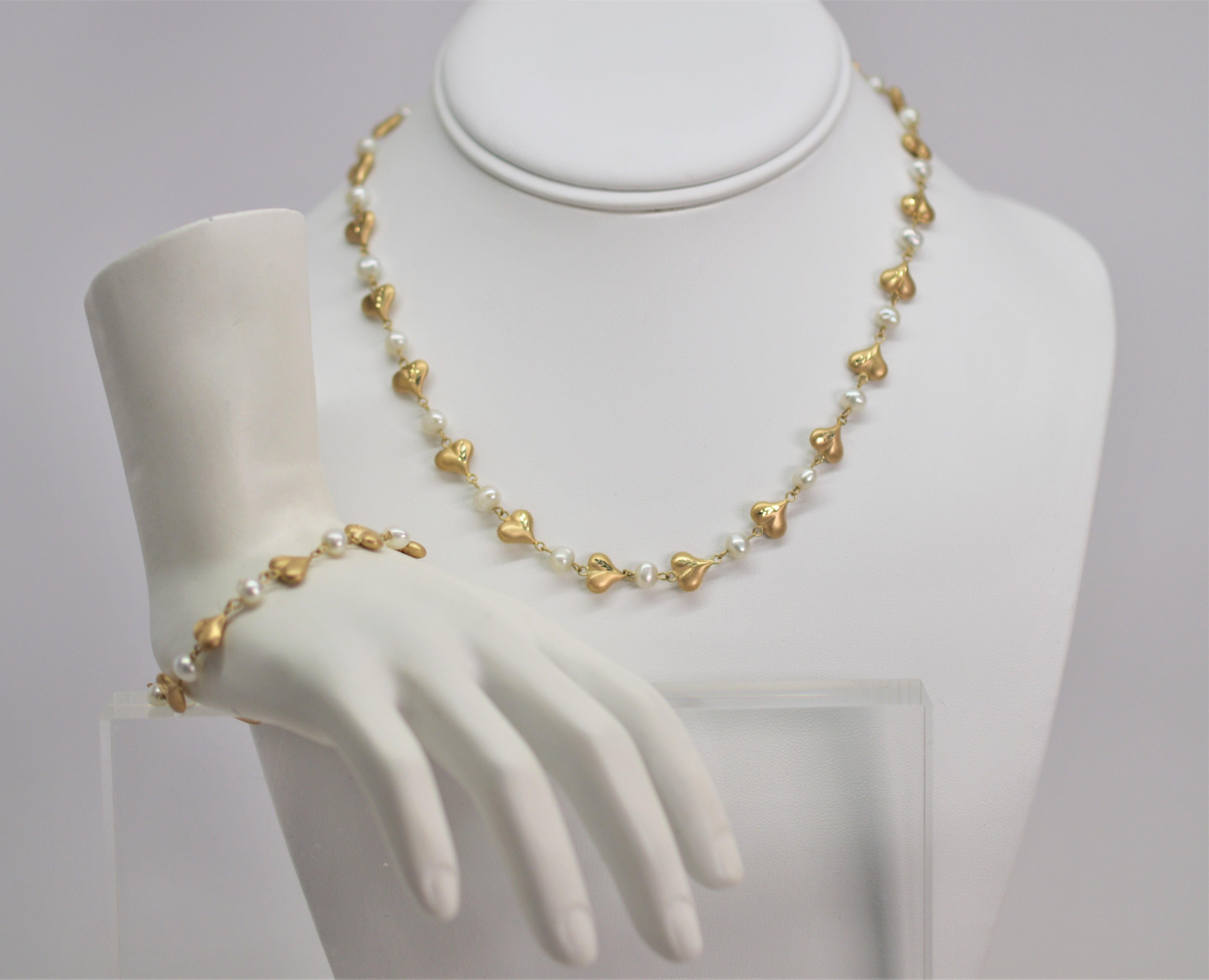 Youthful, this adorable set includes a sixteen inch necklace and seven inch bracelet of flirty satin finish fourteen karat (14K) heart-shaped puff charms alternating with complementing 5.5 mm pearls. Stamped 14K. The maker is unknown. Perfect gift