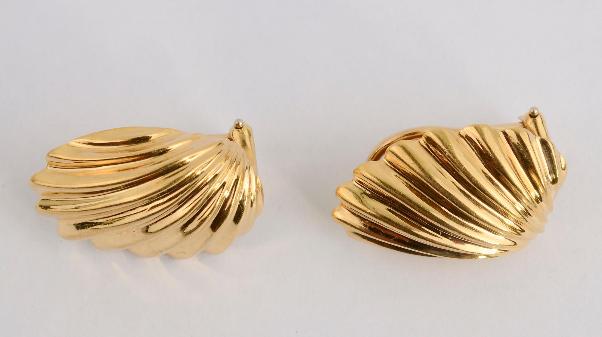 Eighteen karat gold shell earrings that are a bit unusual in that the shape is not symmetrical. One side is more flat than the other which allows it to sit well next to one's face. Backs are posts and clips which can easily be converted to posts
