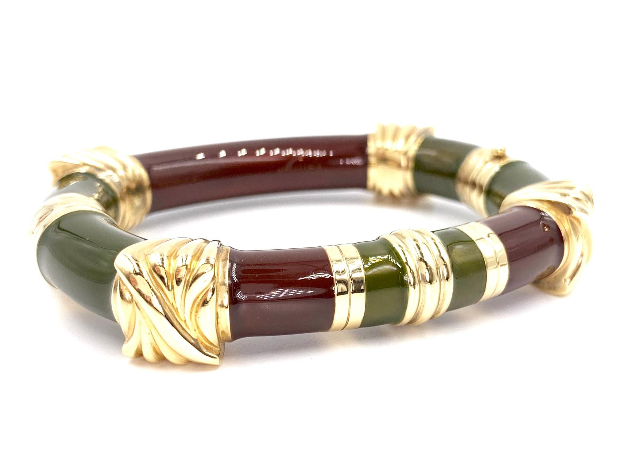This fashionable bangle is made from sterling silver that has been hand painted with deep chocolate brownish-burgundy and olive green enamel with 14 karat yellow gold accents. Width of bangle measures 10mm at the rounded enamel areas and 14mm at the