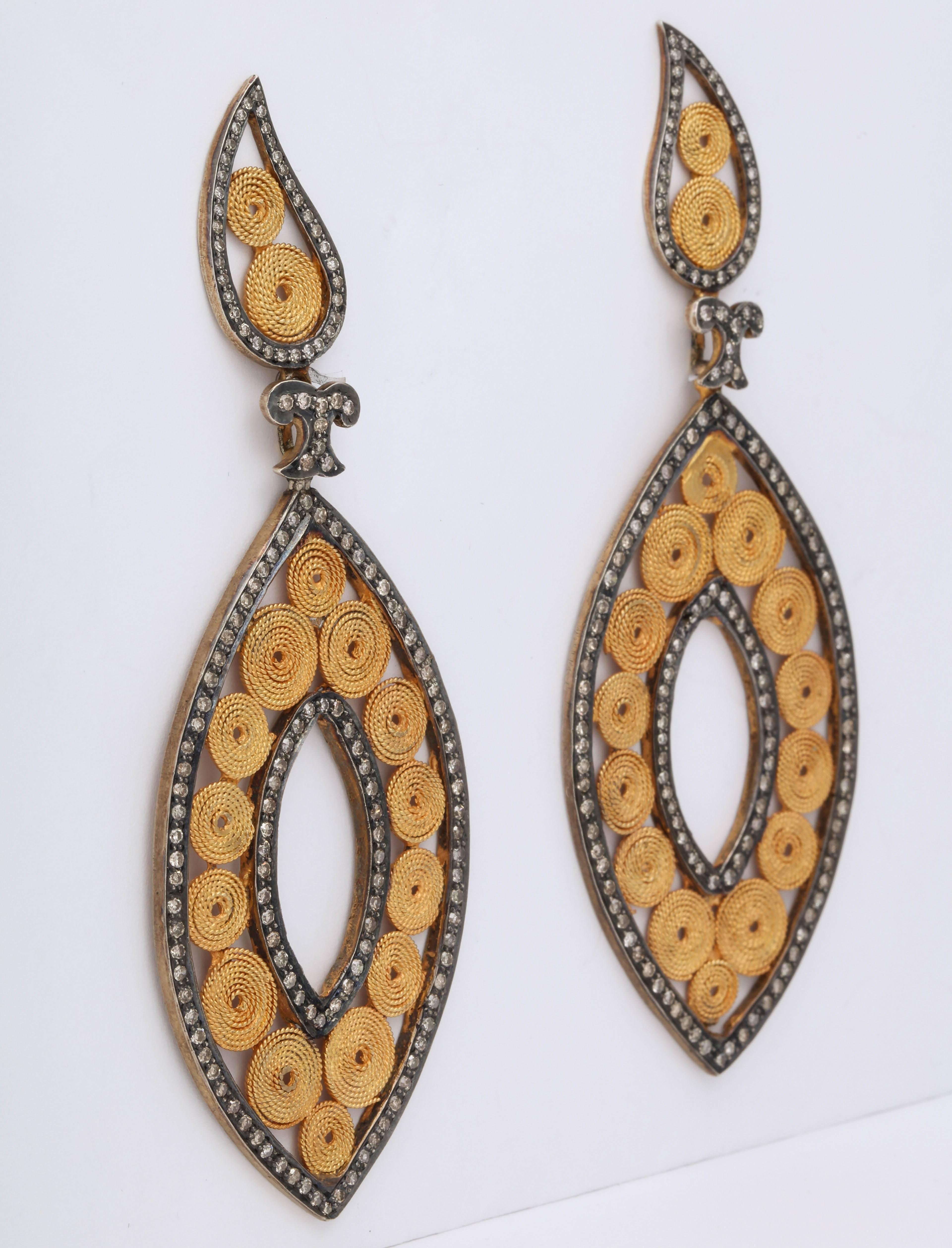 A pair of earrings composed of 18kt yellow gold coiled wire discs set into rhodium plated sterling silver paisley and navette frames set with diamonds.  There are 2.65cts of diamonds.
LengthL 3.52 inches
Width of navette: 1.26 inches
Length of