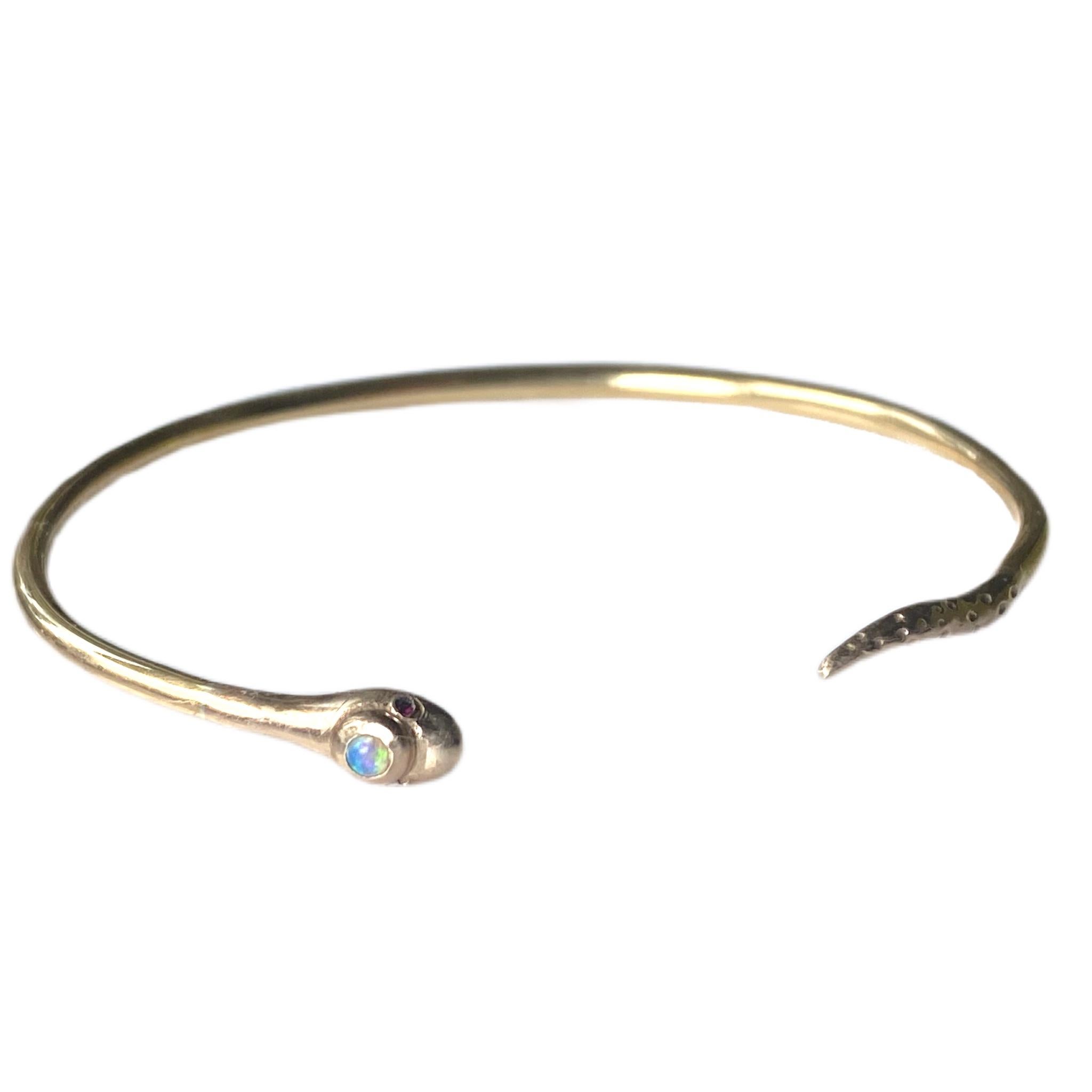 Opal Snake Bracelet in 14 Karat Gold with Ruby Eyes 

Embrace mystical beauty with this enchanting 14K gold snake bracelet, featuring vivid ruby eyes and a luminous opal gemstone set in the serpent’s head. Handcrafted with precision, this delicate