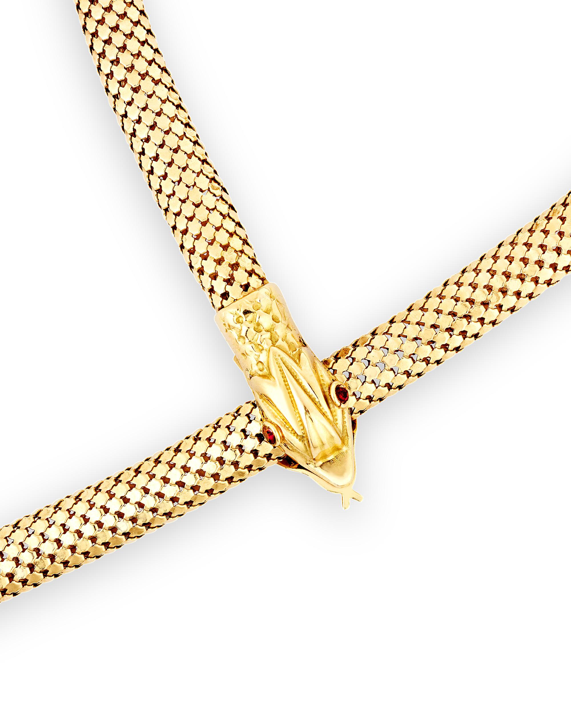 Elegant and unique, this sophisticated 18K gold necklace takes the shape of a snake. The lustrous necklace is composed of a beautiful gold cord complete with scale-like details and a snake head and tail. The snake's head is embellished with two red