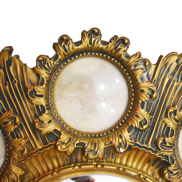 A beautiful gold starburst style convex mirror with 8 round photo frames surrounding. Created from plastic, (we believe by Syroco) this lovely piece is created from plastic. At it’s center, a convex mirror. It is surrounded by 8 smaller round convex