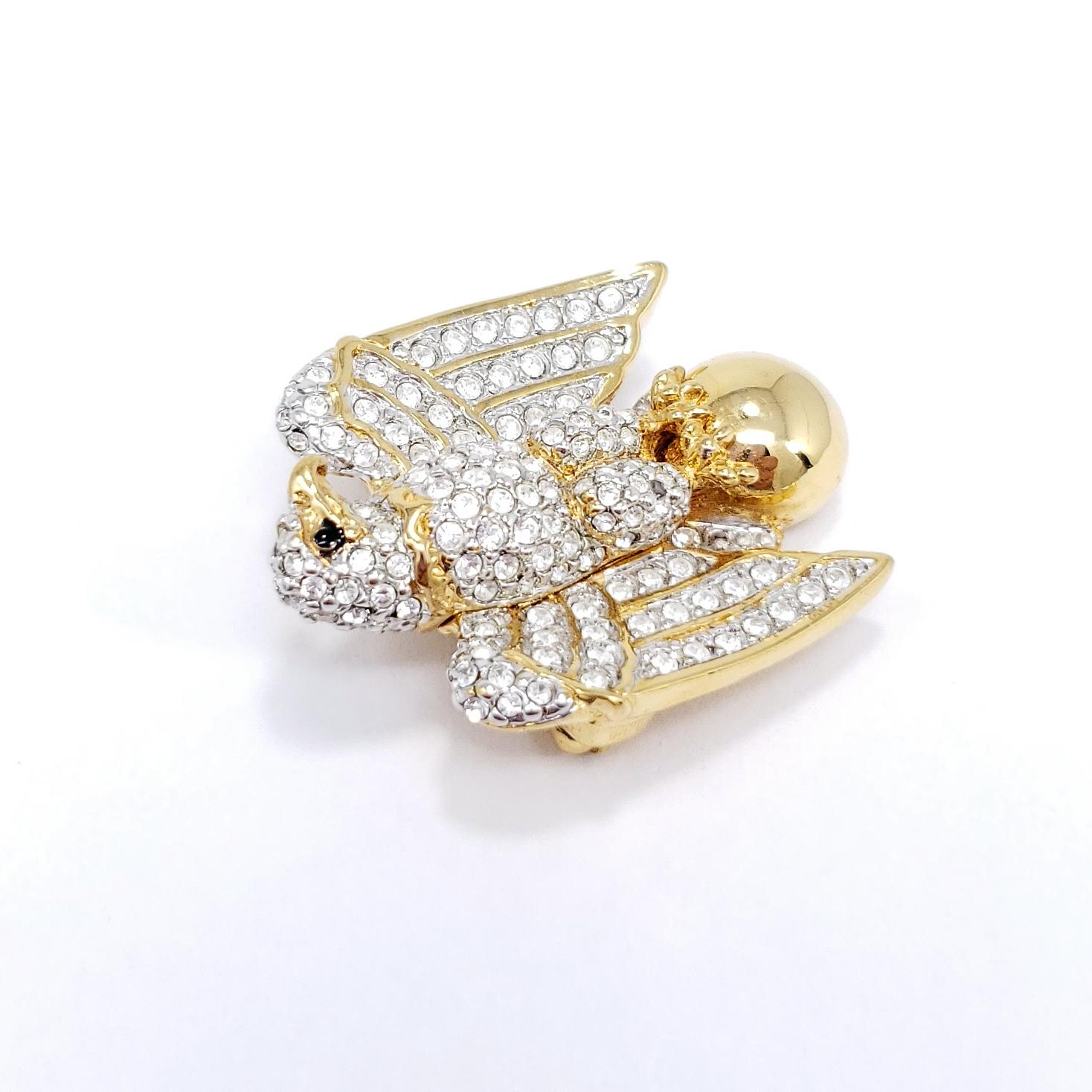 A regal pin brooch in gold. This eagle is decorated with clear Swarovski crystals for a sparkling, glamorous, look.

Gold plated.

Hallmarks: Swarovski Swan