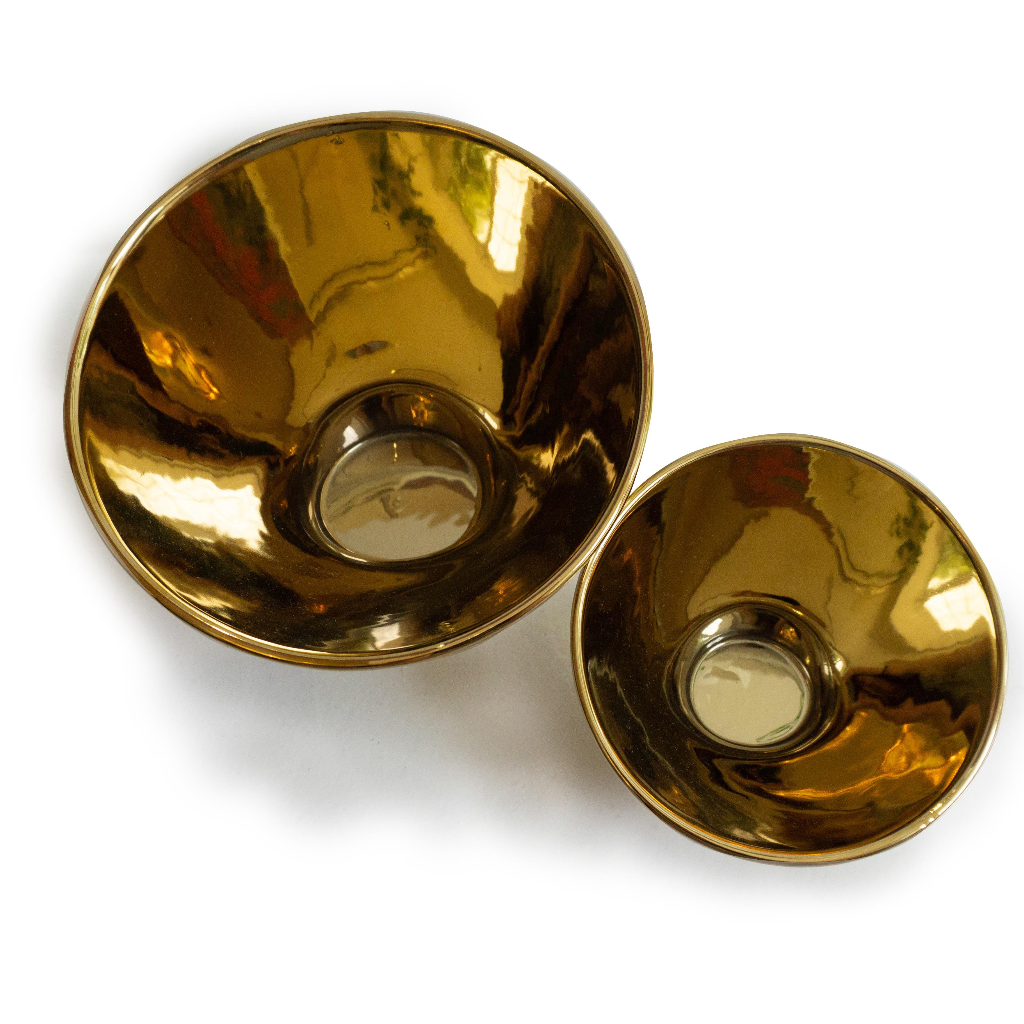 A set of gold tea light holders. These votives glow with a magnificent reflective effect in dark settings. 

Designed by Jacob de Baan

Dimensions: Large - 5” height x 7” diameter small - 3” height x 4” diameter.

 