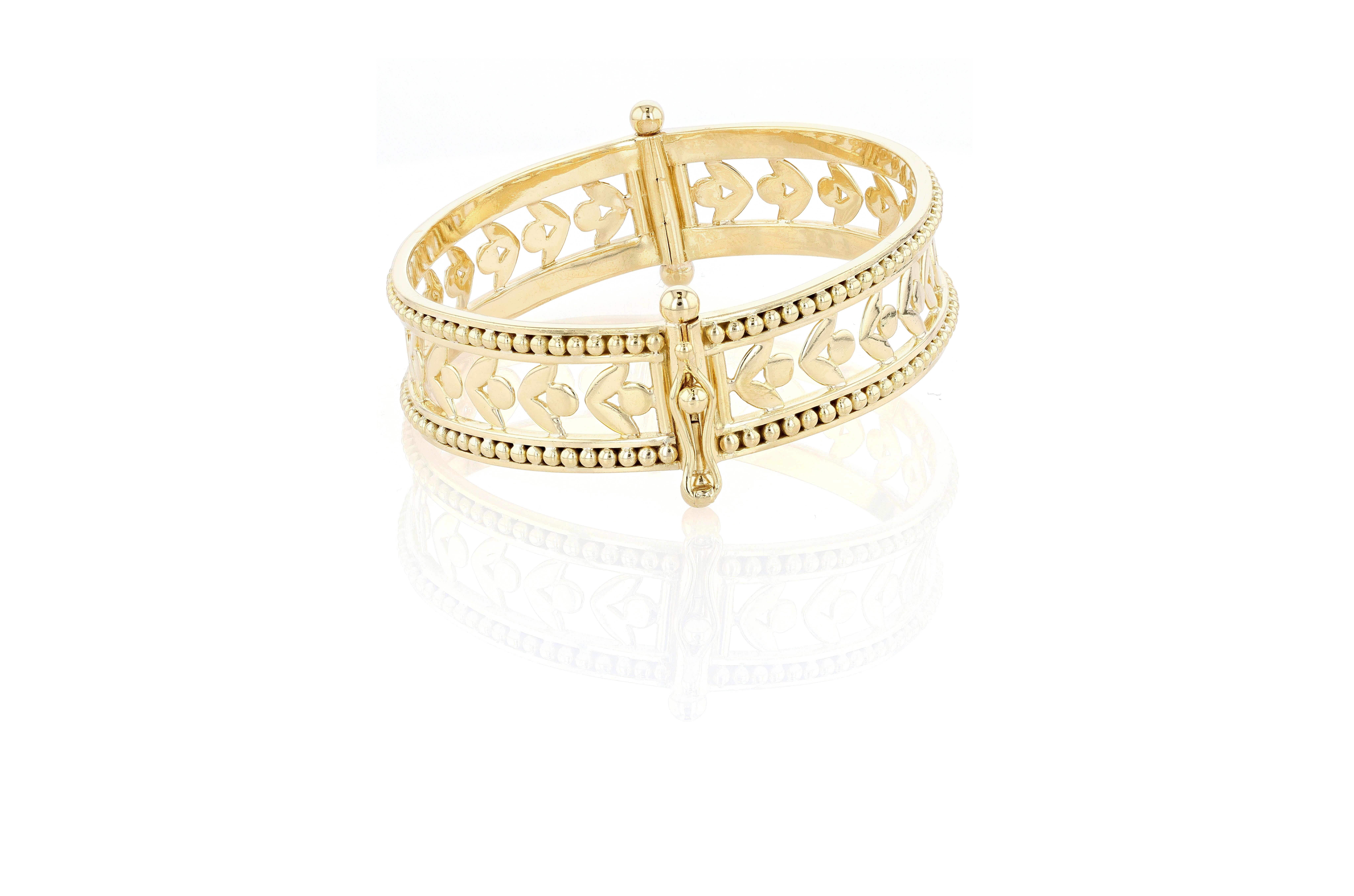Brazalete de oro amarillo de 18 quilates, calado y con bisagras, de Temple St. Clair, que representa un motivo de enredadera que se repite, bordeado a ambos lados por cuentas de oro. Este brazalete está articulado por un lado y tiene un cierre de