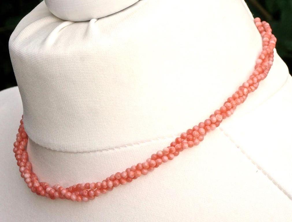 
Gold tone and triple strand necklace with coral beads that vary in colour from dark salmon pink to pale salmon pink. Length 42cm / 16.5 inches, and the beads are diameter 3mm / .12 inch. The necklace can be worn twisted or loose.

This is a