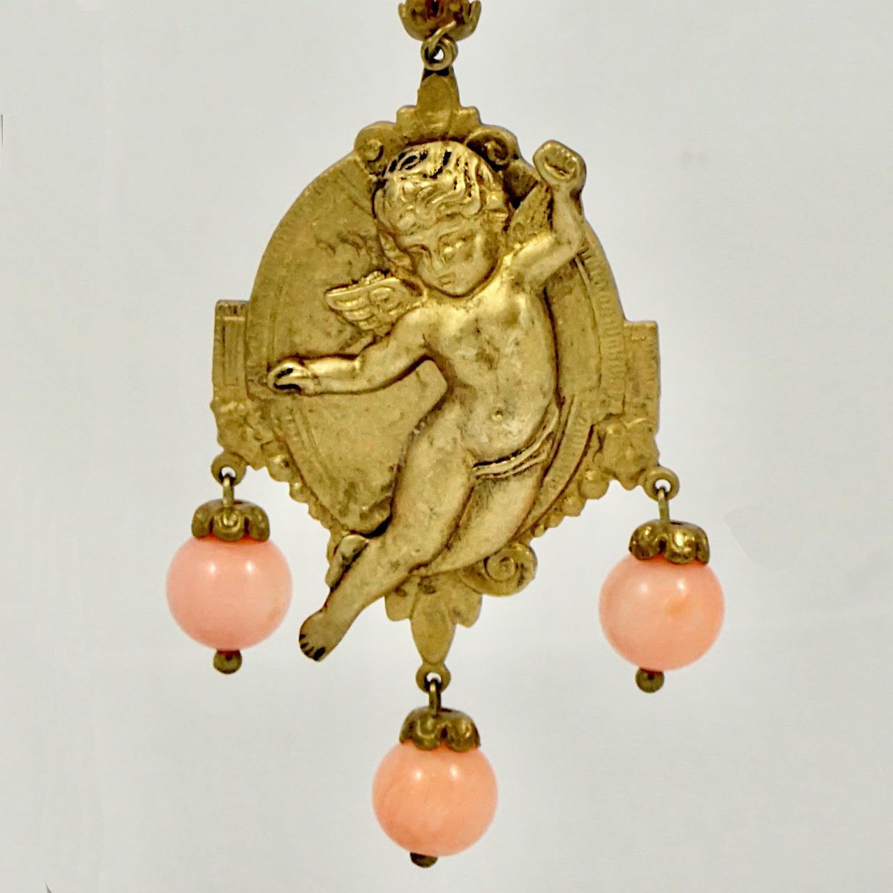 Fabulous gold tone cherub lever back earrings, with lovely angel skin coral drops. Measuring length 8.5 cm / 3.3 inches including the lever backs, by width 2.85 cm / 1.1 inch.

This is a beautiful pair of vintage cherub earrings, circa 1960s. A rare