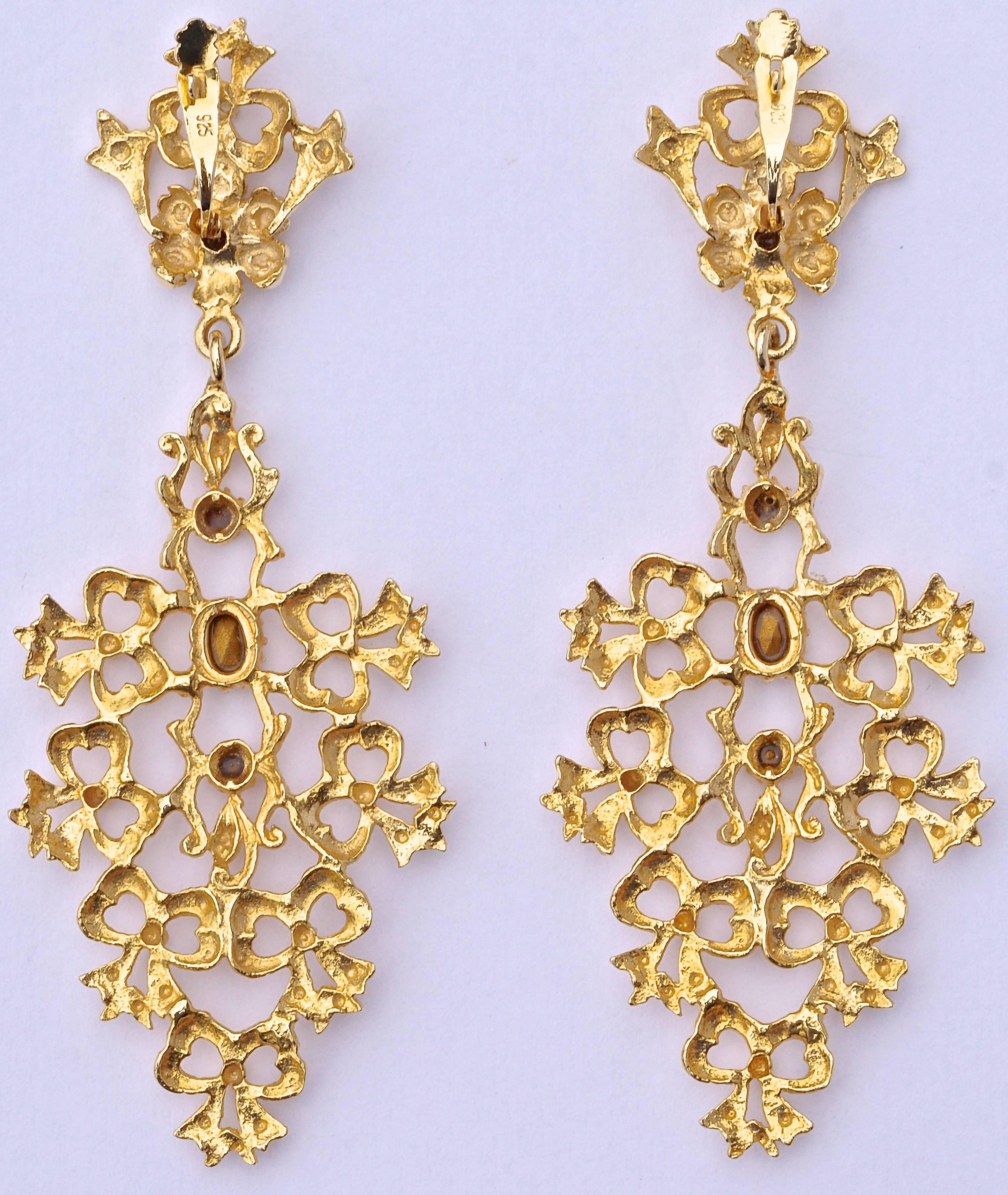 Gold tone chandelier earrings for pierced ears in an unusual bow design, and set with four clear faceted rhinestones. The top has a flower embellished with a rhinestone. Length 8.2cm / 3.23 inches by maximum width 3.2cm / 1.26 inches. They are in