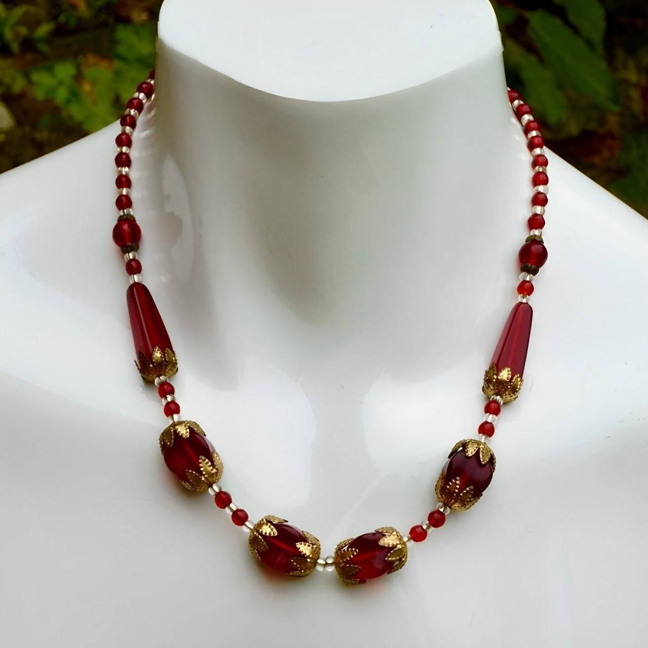 Splendida collana ornata in tonalità oro, con perle di vetro rosse e trasparenti. Misura la lunghezza della collana 46,2 cm / 18,1 pollici. La collana è tutta originale e probabilmente è ceca.

Questa bellissima collana di vetro rosso risale agli