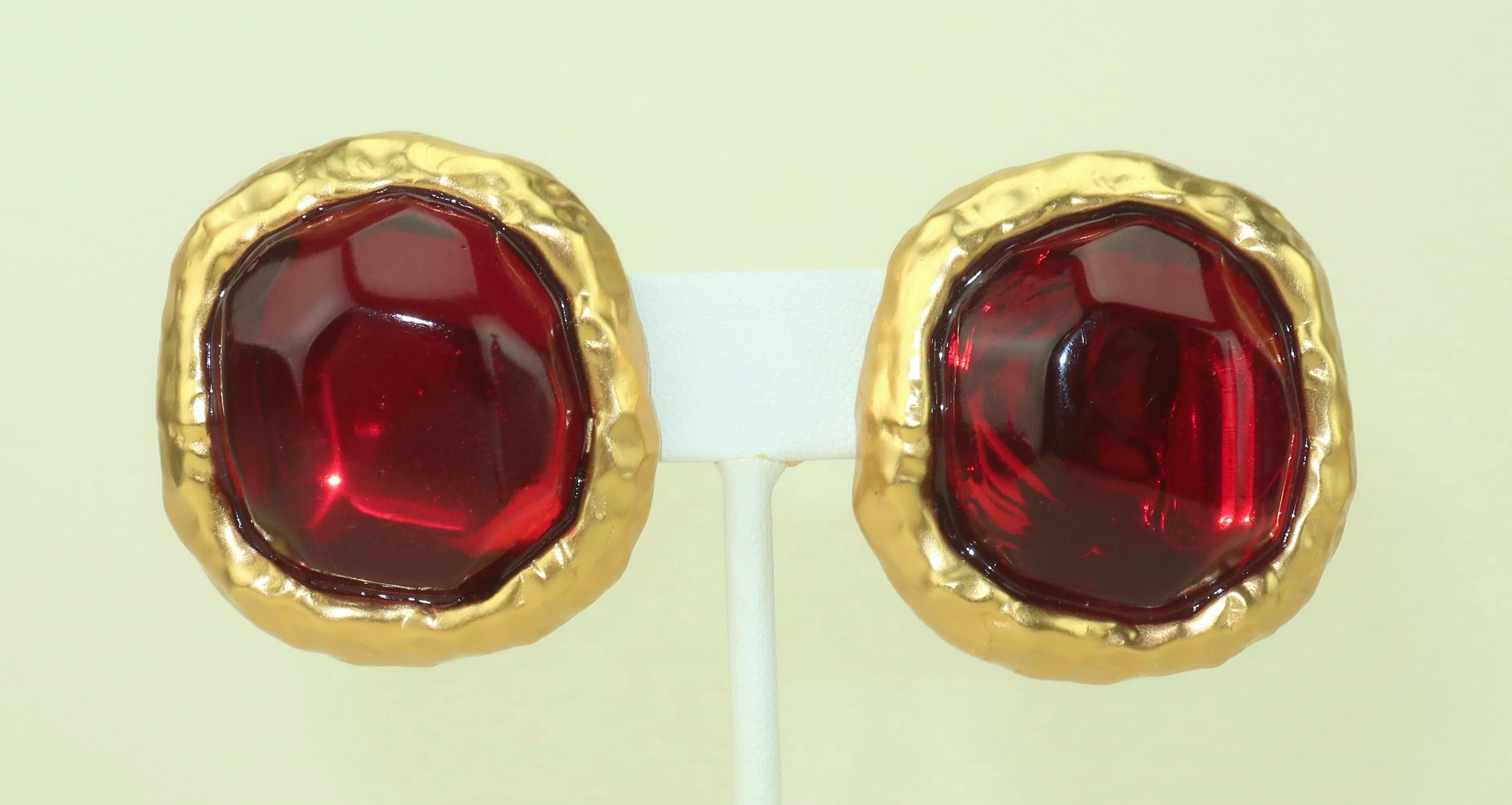 Orecchini anni '80 con base in metallo dorato spazzolato e centri in resina rossa sfaccettata.  La sfaccettatura del centrotavola in resina rossa crea una superficie riflettente simile a una vasca d'acqua.  La base in metallo dorato ha un'estetica