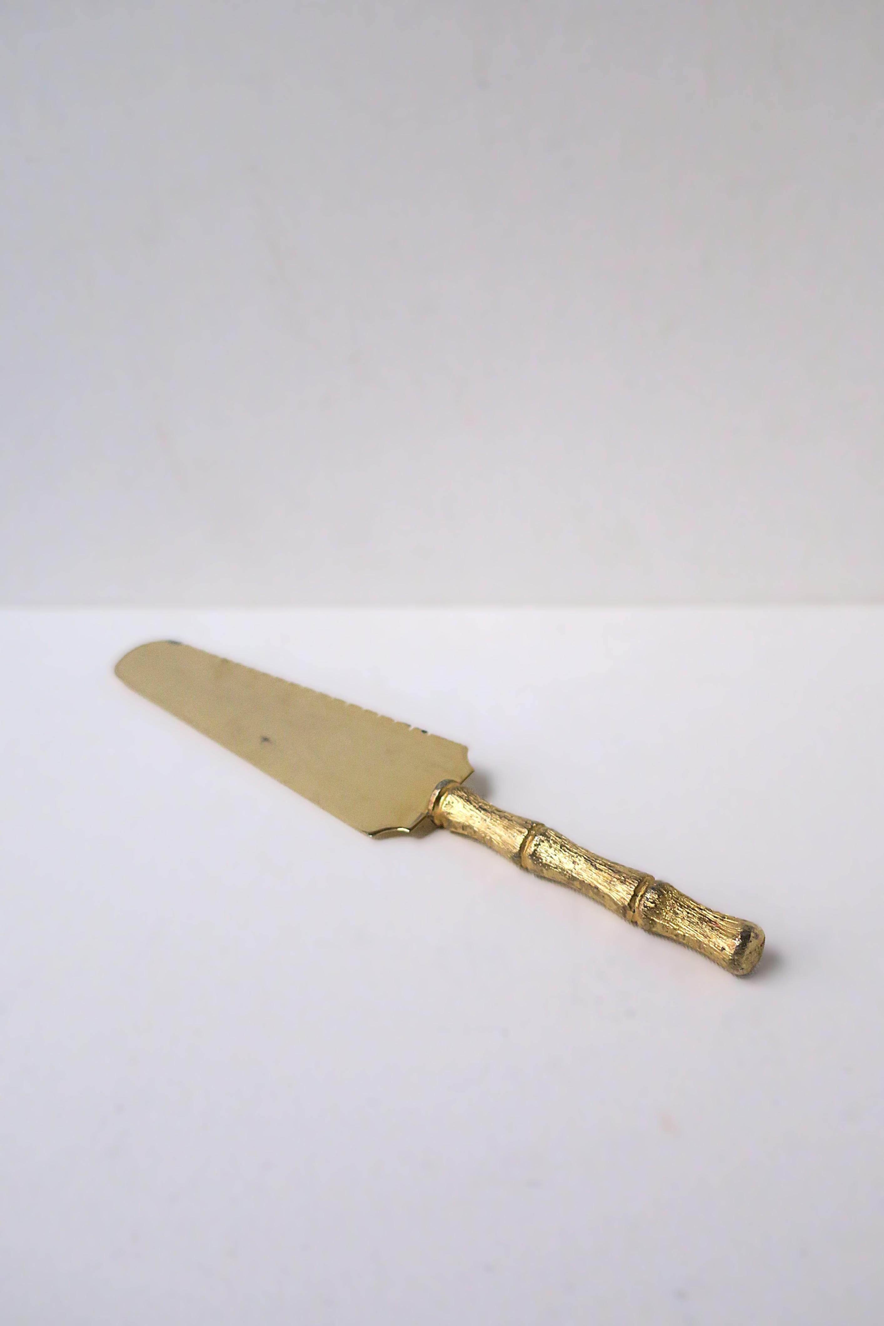 Un servizio da tavola in tonalità oro con manico in stile bambù, anni '60 circa. Il pezzo è in acciaio inossidabile (come da marchio) rivestito in oro dorato con manico in stile bambù e bordo seghettato per tagliare/servire. Un ottimo pezzo per