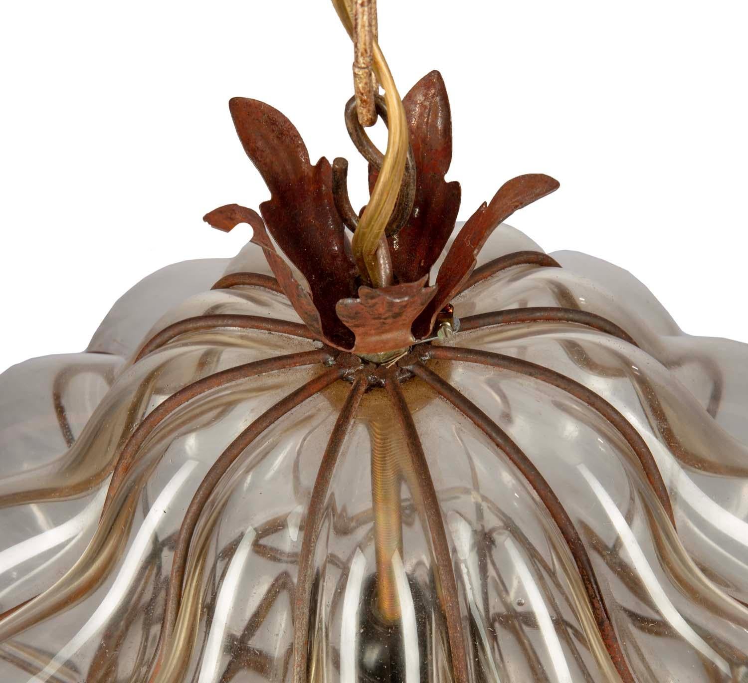 Suspension de forme classique datant du milieu des années 70, avec verre enveloppé de fer et orné de feuilles d'or décoratives au niveau de la couronne et de la base. 
Chaîne de 69