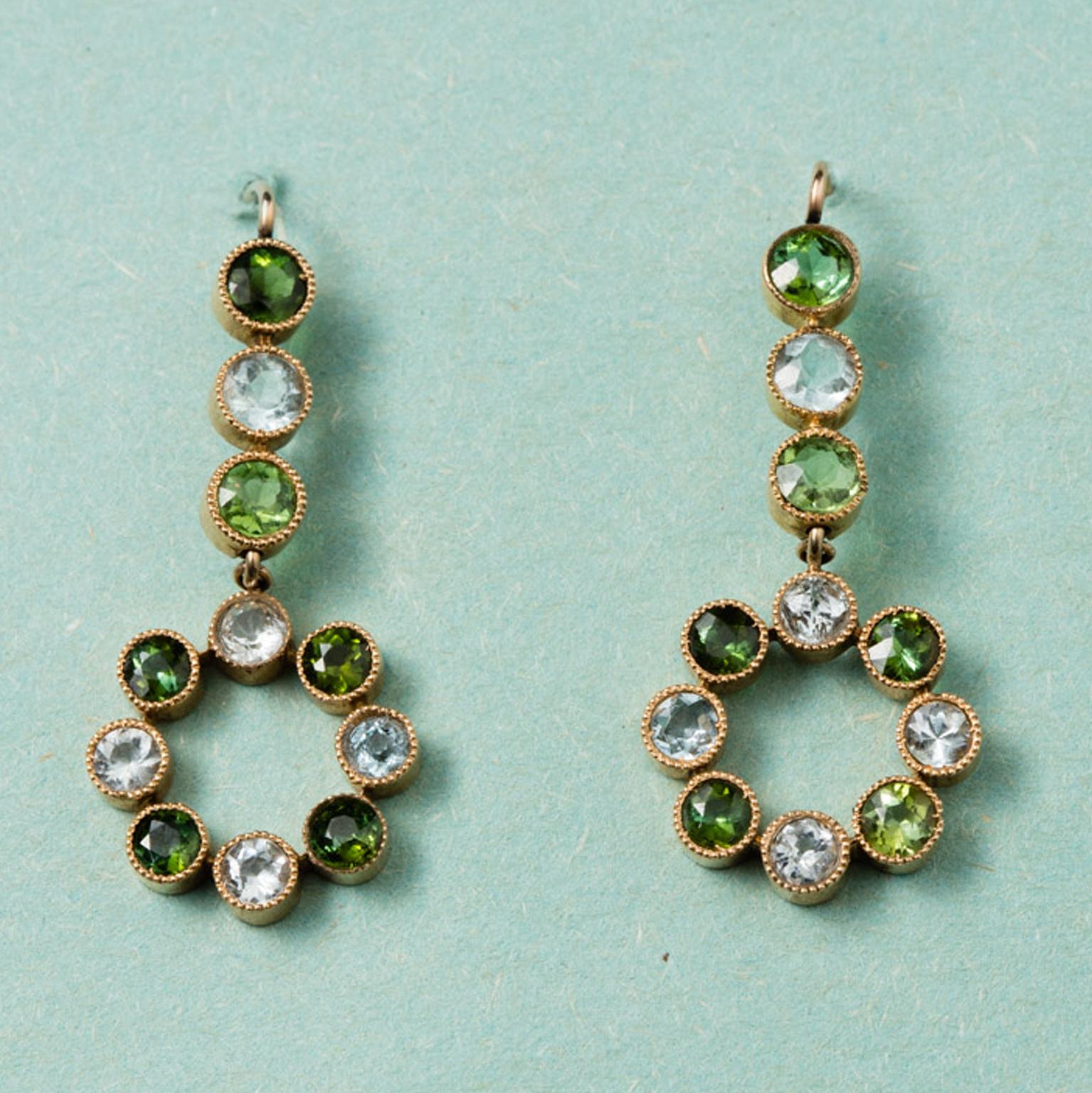 A pair of 15 carat gold earrings with a circle where round aquamarines alternate green tourmalines, circa 1910, England.

weight: 5.7 grams
dimensions: 3.7 x 1.5 cm