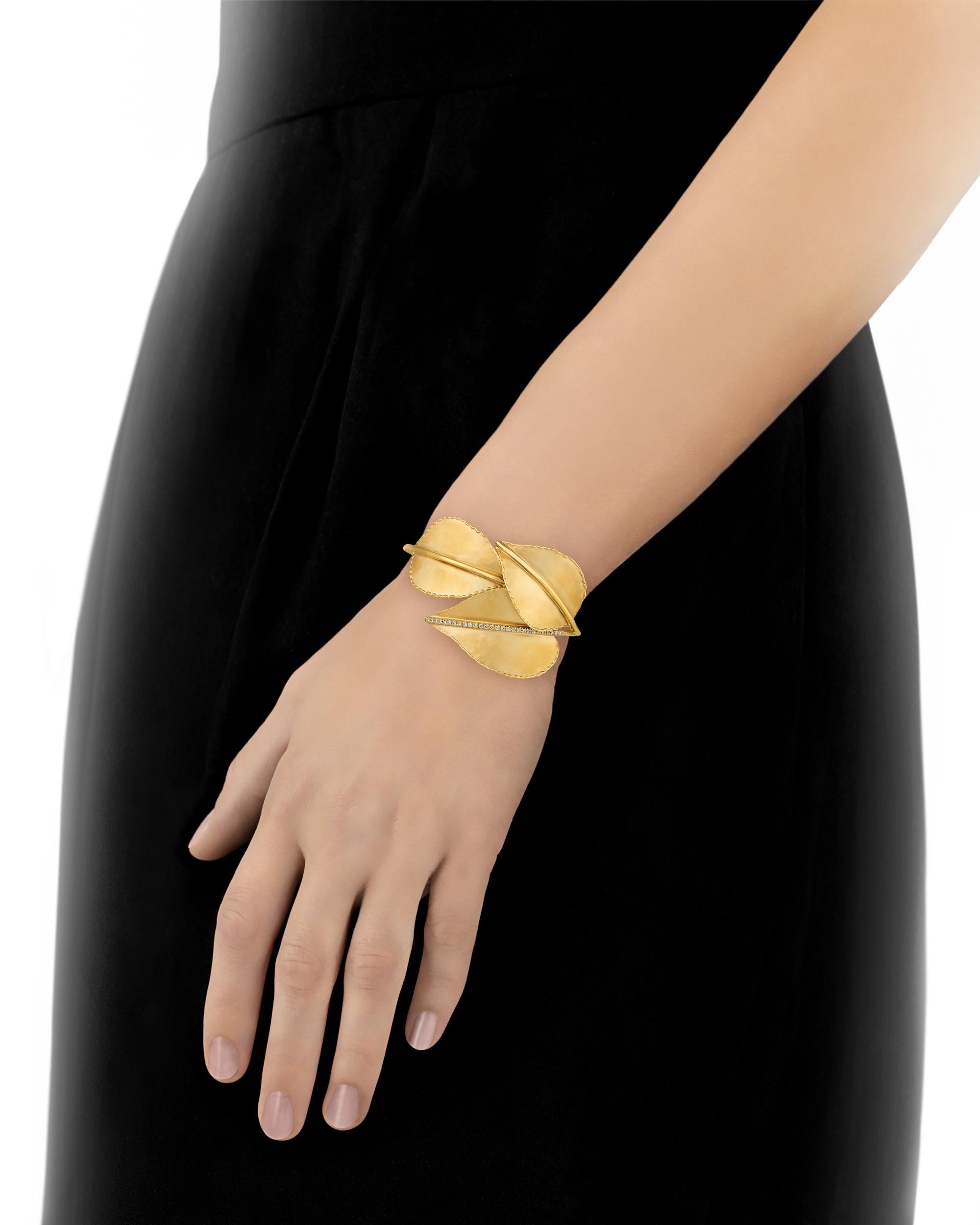 This elegant and charming bracelet is composed of three beautiful golden leaves artfully arranged to form a bangle cuff. The lustrous 14K gold bangle is accented by sparkling white diamonds totaling 0.28 carat. The unique design exudes whimsy and