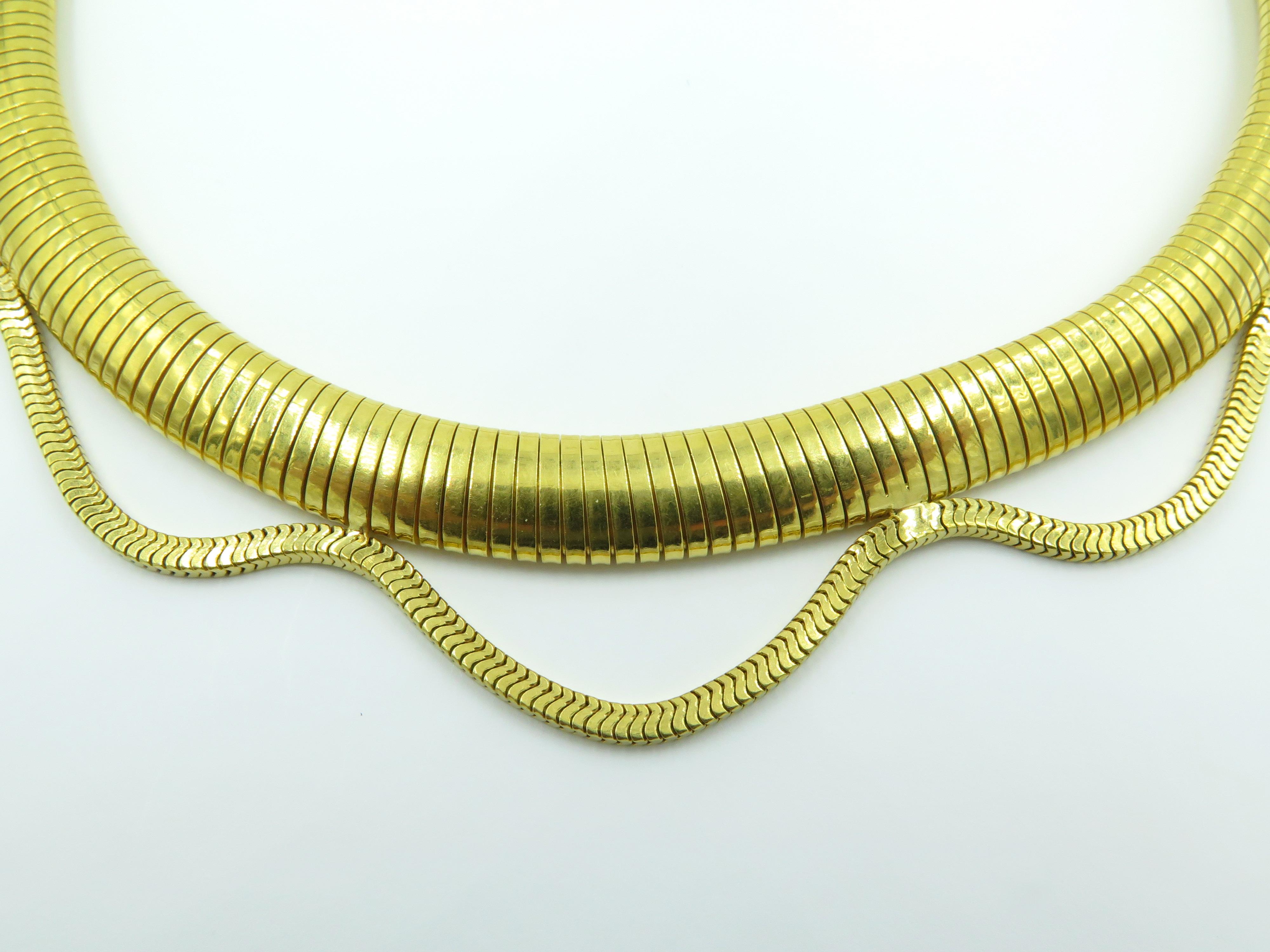 A 14 karat yellow gold necklace. Circa 1940. Designed as a tubogas collar, suspendng an undulating snake chain. Length is approximately 14 inches, gross weight is approximately 83.1 grams.