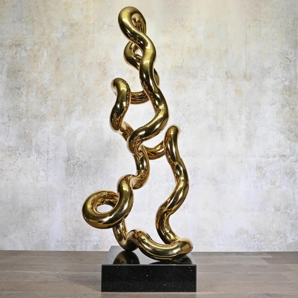Die Gold Tubular Sculpture ist ein zeitgenössisches Metallkunstwerk, das vom Bauhaus-Röhrendesign inspiriert ist, das den Modernismus des 20. Die ineinander verwobenen Kurven erzeugen ein Spiel aus Bewegung und Licht.
Auf einem Sockel aus schwarzem