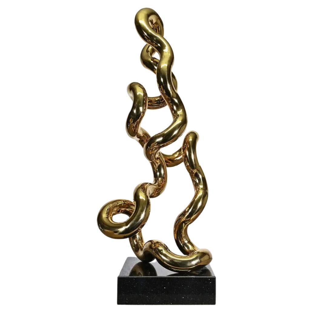 Sculpture tubulaire en métal doré sur socle noir, style contemporain