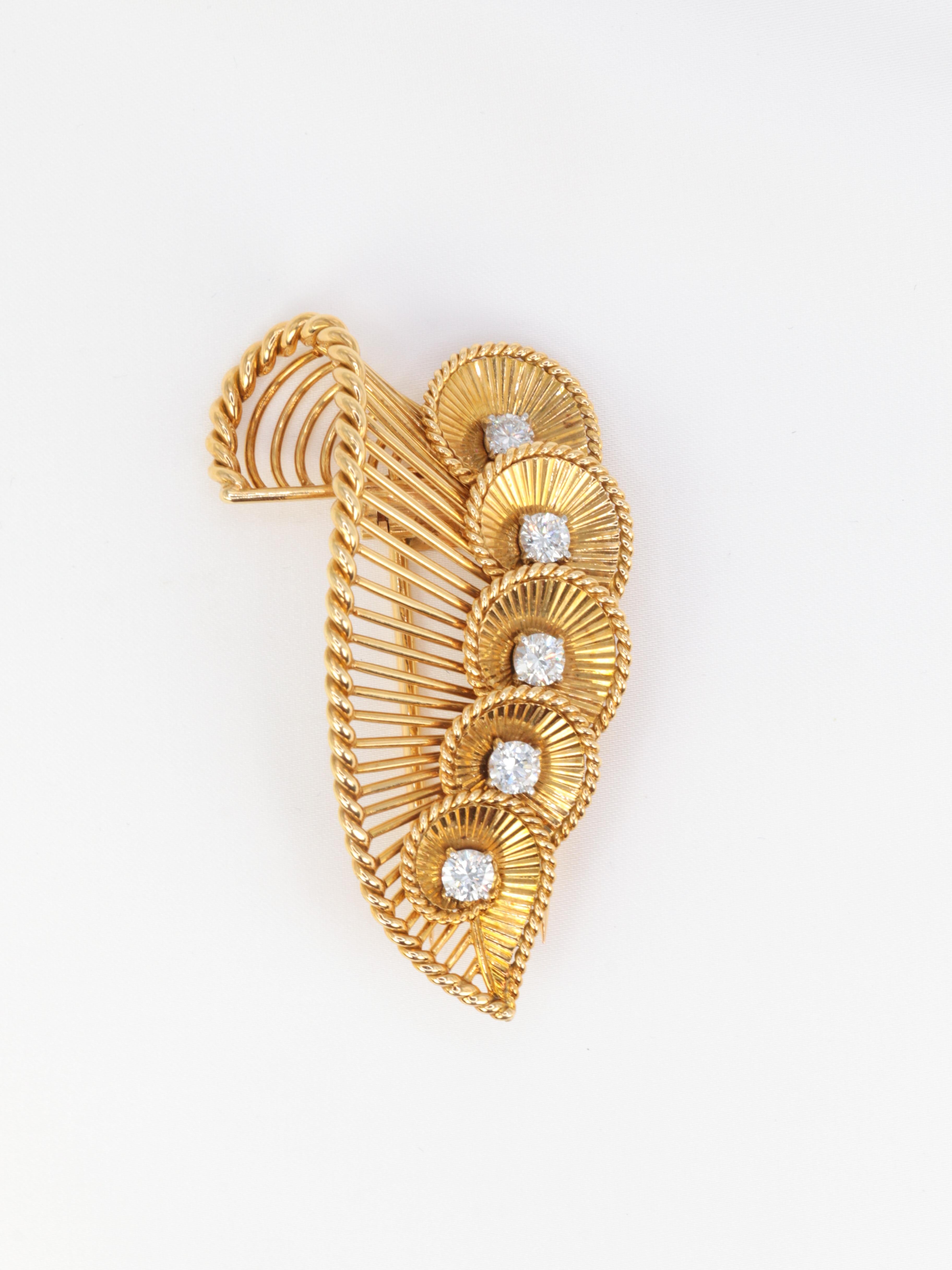 18Kt gold (750°/°°) Brooch featuring a succession of falling shells placed on a larger pattern recalling the shape of the previous ones. 
The shells are formed of rays and delimited by a twisted gold wire. The shells are set with high quality