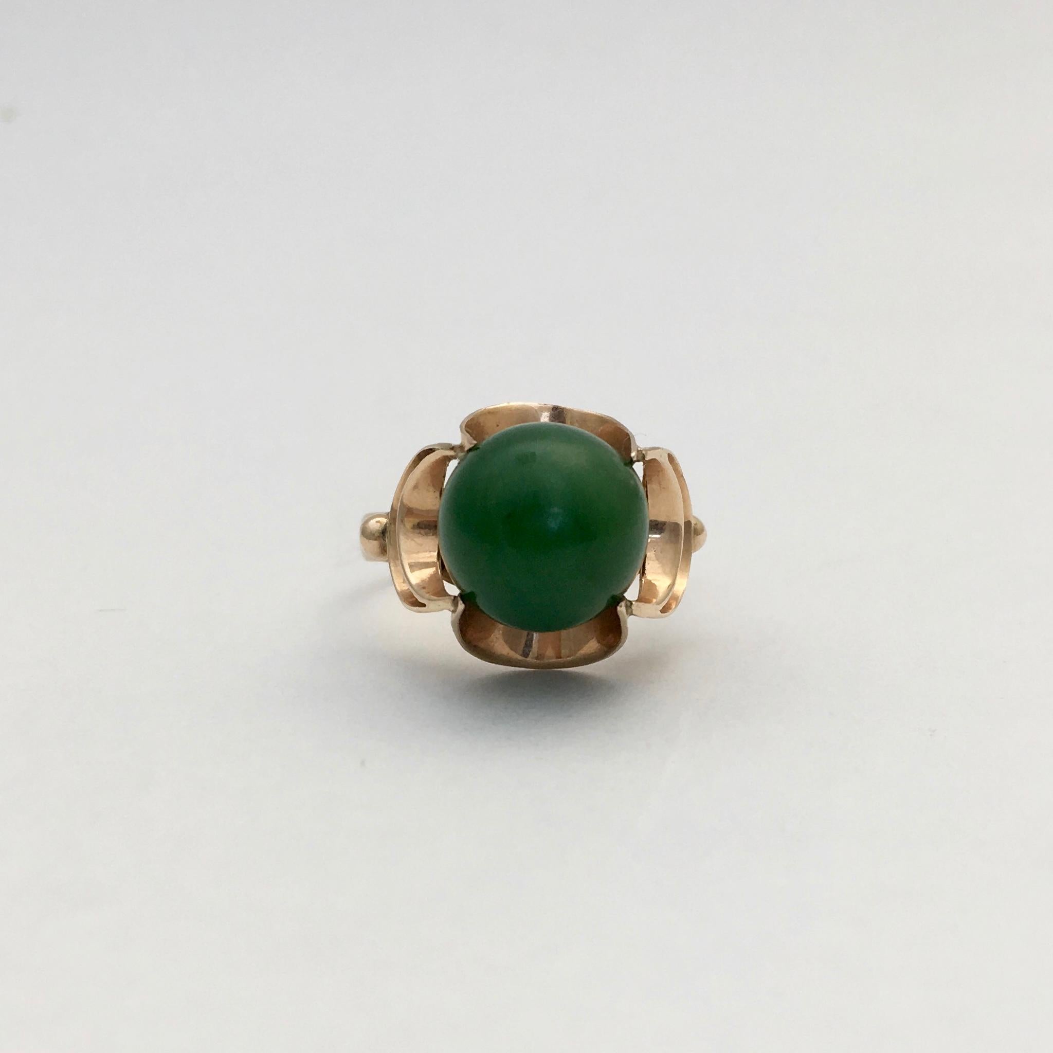 This striking and unusual jade ring has a modernist air. The spherical jade stone is set tantalisingly within an abstract floral-esque setting. The lush green of the stone is clear and unmarked. There is no date mark on the ring, but it has an