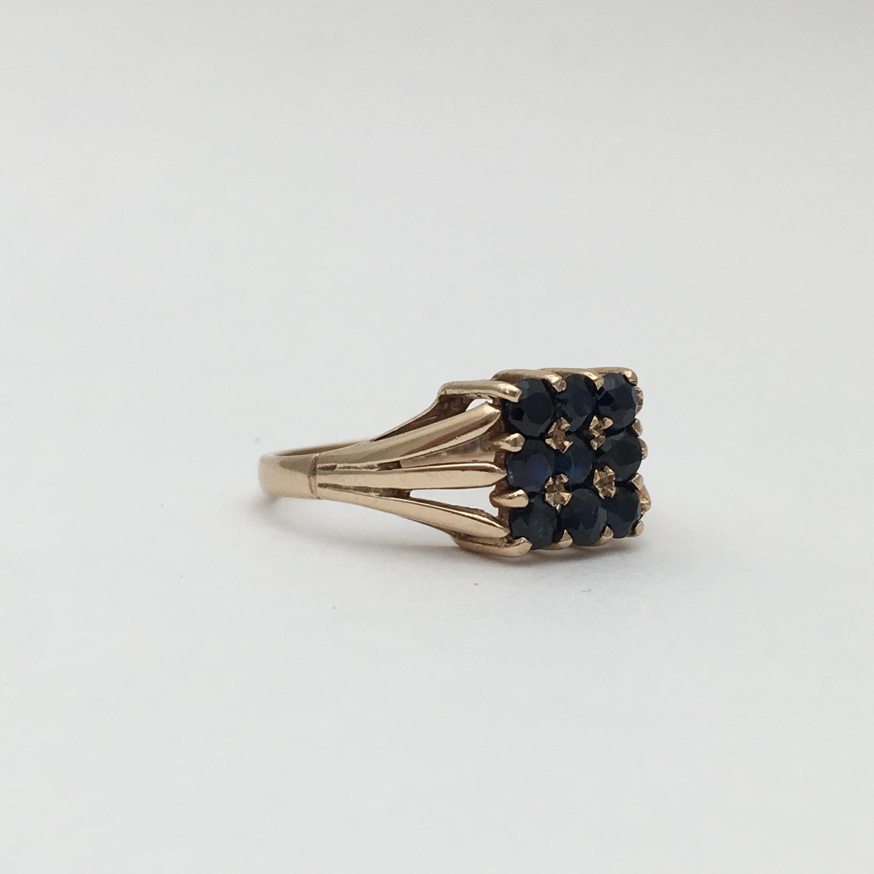 This stylish gold ring is set with nine faceted sapphires in deepest navy blue. The combination of the colour and square setting make for a very chic item, which dates from 1976. It was assayed in Birmingham, England and includes the makers mark
