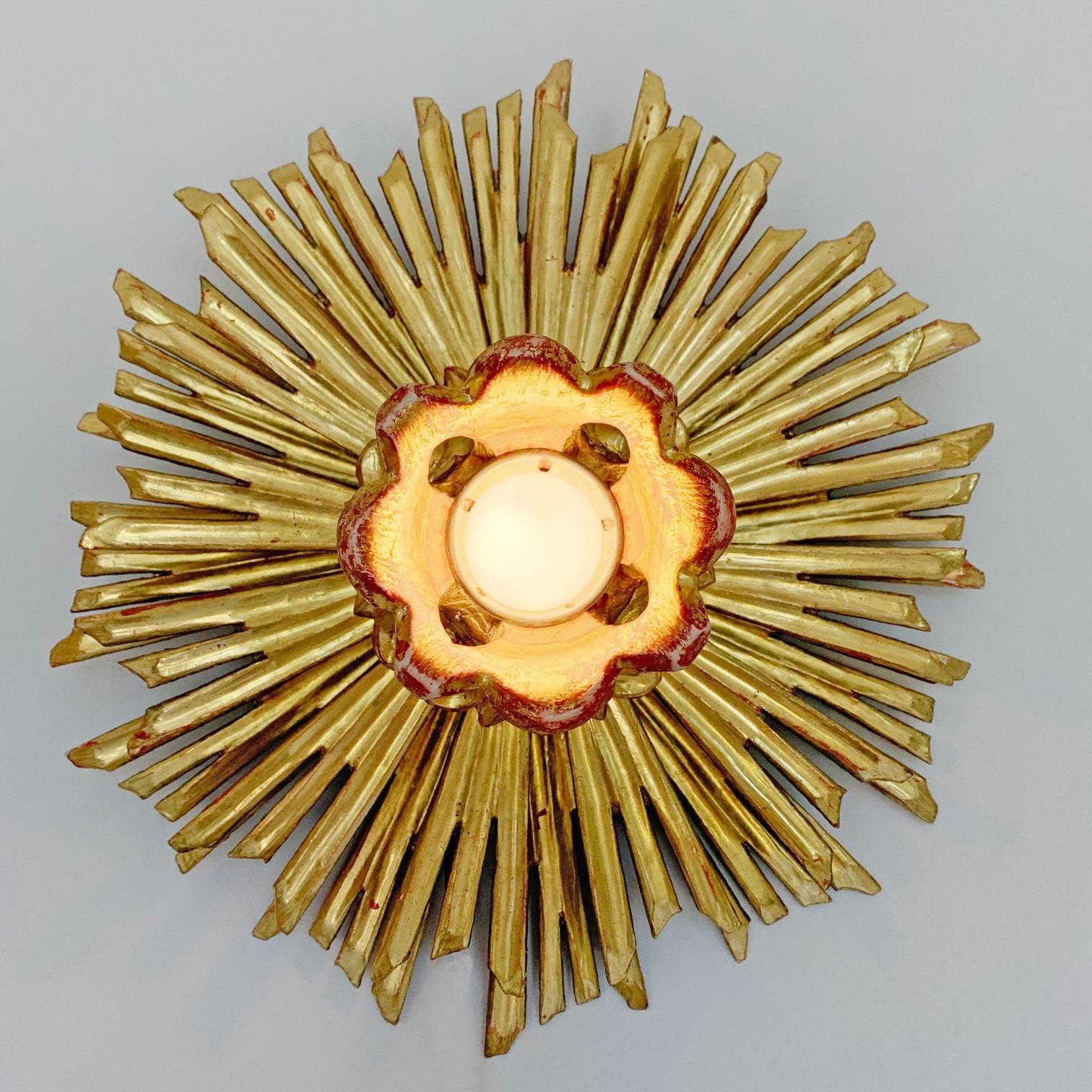 Fabulous 1930's water gilded sunburst flush mount. Carved wooden rays surround the single lamp holder to the centre, originally from a church in Germany this piece is in absolutely glorious condition, the bright gold gilding is superb.

These