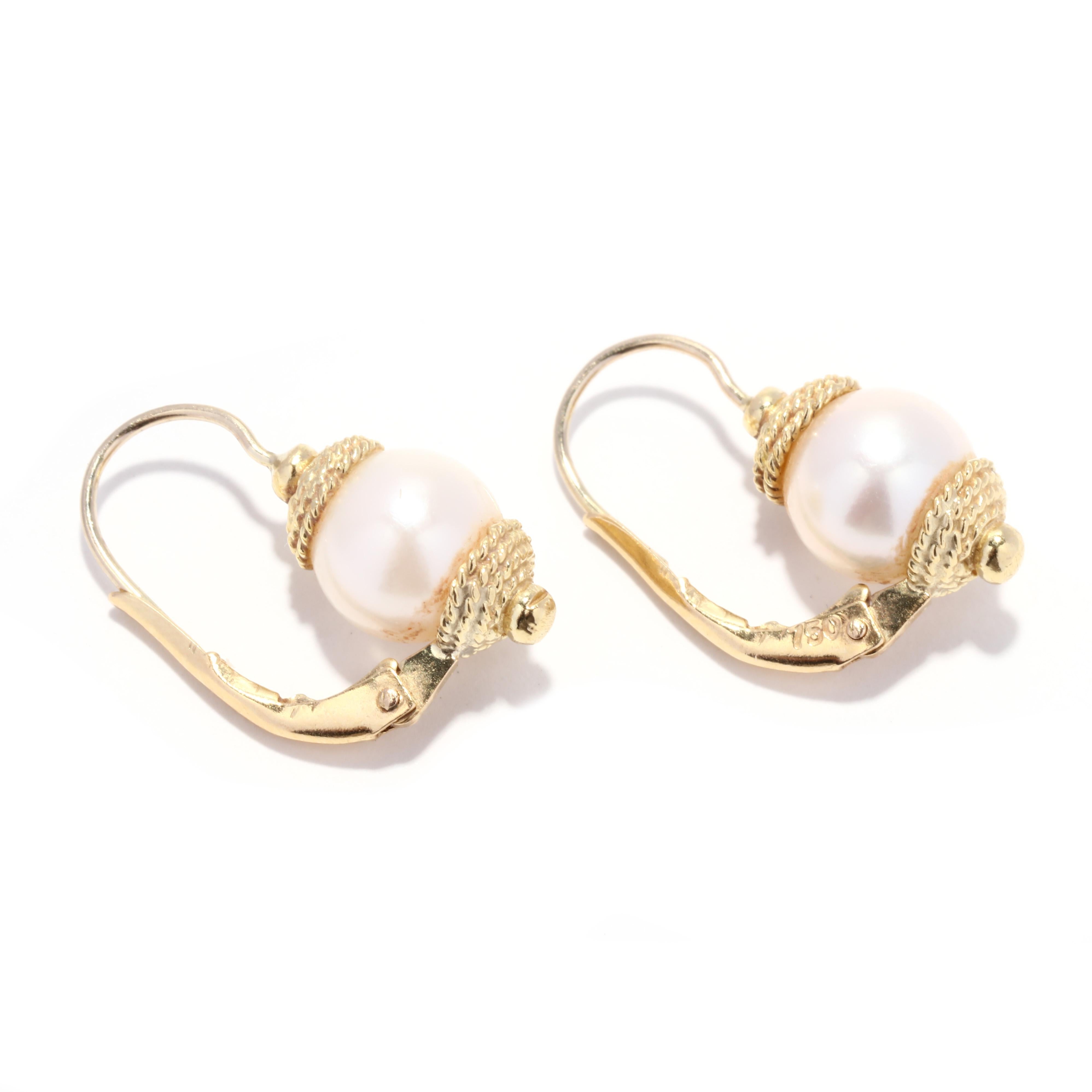 Ein Paar Vintage-Ohrringe aus 18 Karat Gelbgold mit weißen Perlen. Diese klassischen Ohrringe bestehen aus 8 mm großen weißen Perlen mit rosafarbenen Obertönen, Endkappen mit gedrehtem Seilmotiv und durchbrochenen Hebelverschlüssen.

Steine:
-