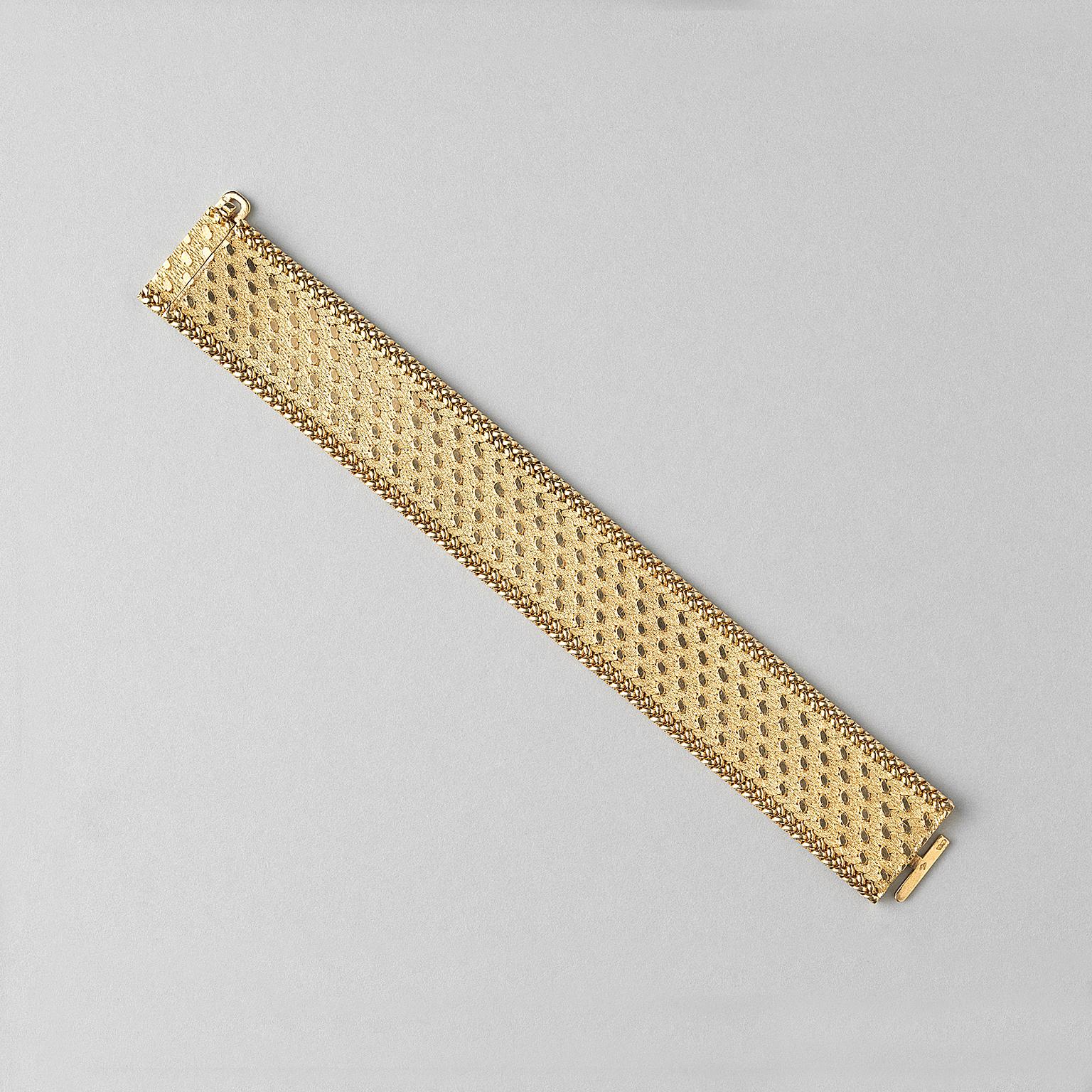 An 18 carat gold flat mesh woven bracelet with a matte textured gold background formed of hammered links with a contrasting geometric raised pattern in polished oval gold dots with a polished braided gold border, with concealed tongue and box clasp,