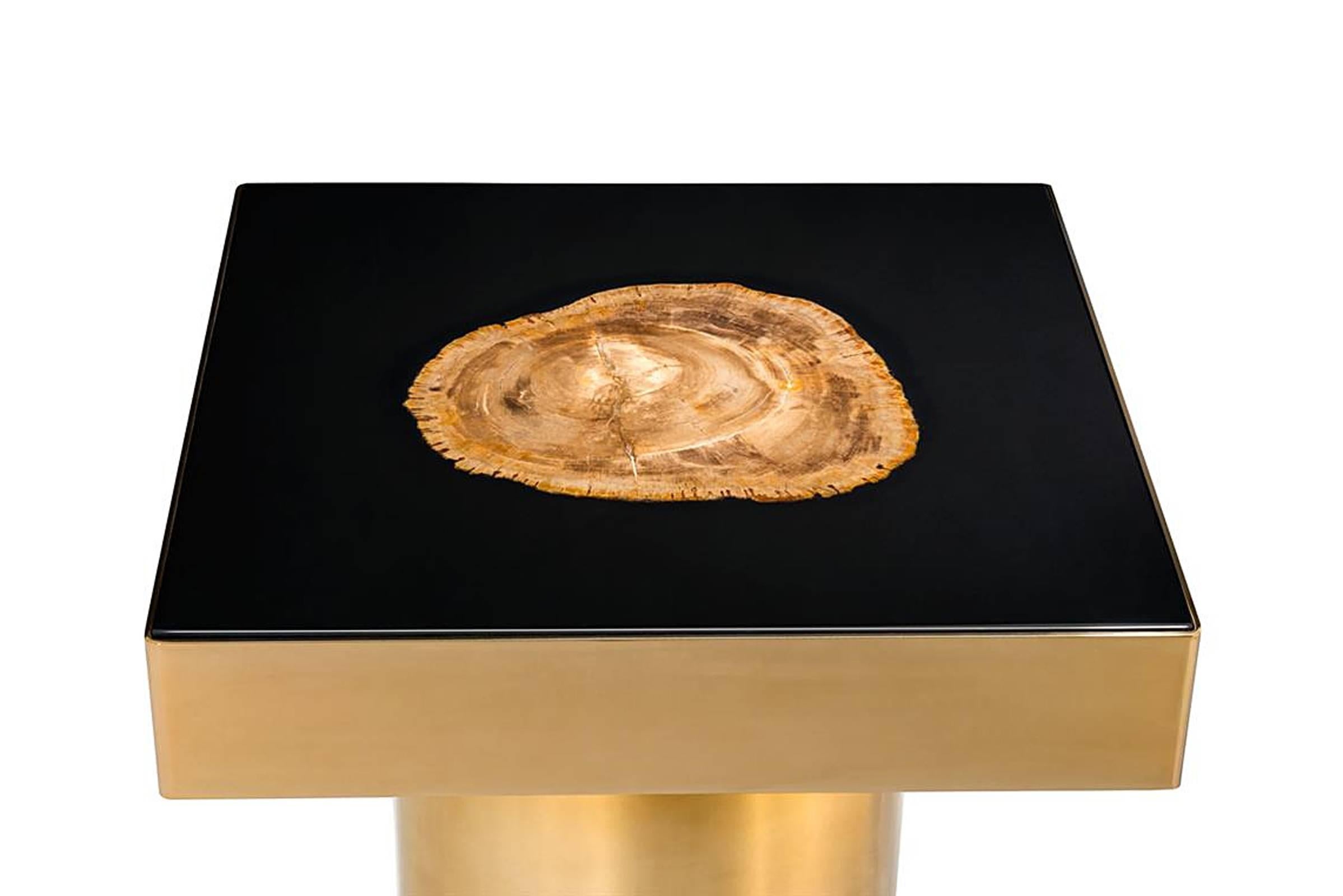 Mesa auxiliar de madera petrificada dorada con estructura de latón en mate 
Acabado dorado, madera petrificada artesanal y tapa lacada en negro.
