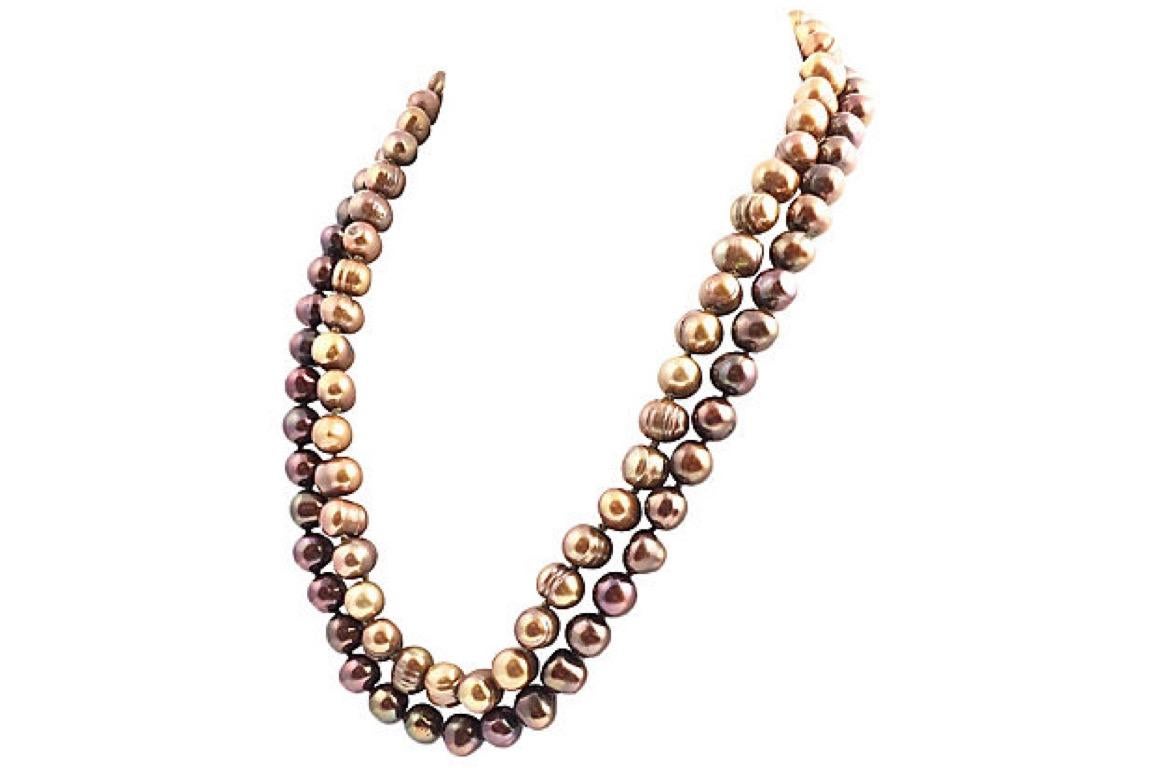 Set of two strands of dyed Chinese baroque cultured pearls. Both necklaces are golden in color but one is a darker mocha brown shade. Each features a sterling silver clasp with a chain that adjusts from 16.5