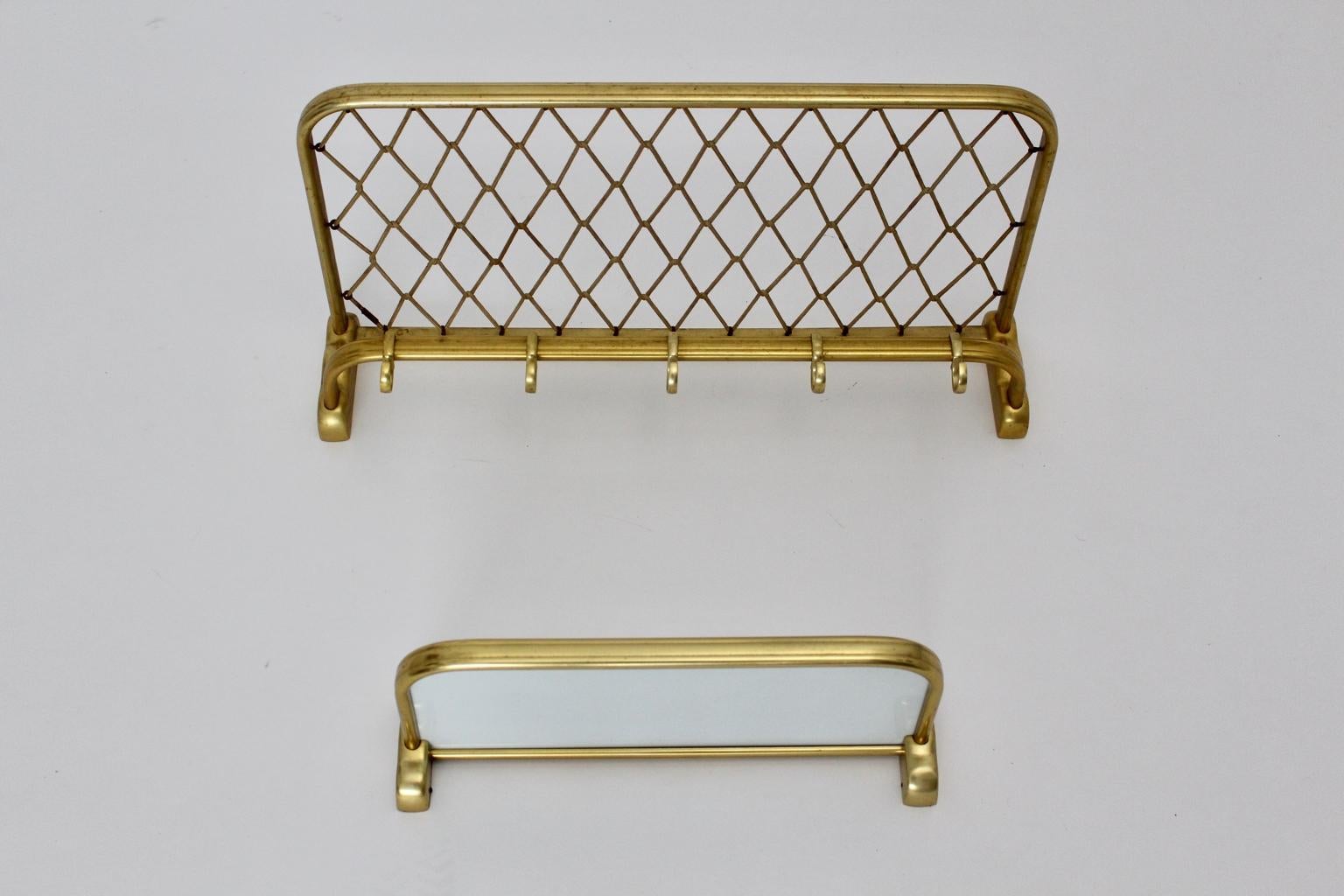 This presented mid century modern vintage wall wardrobe, which was made of golden anodized aluminum, consists of two parts. 
One part was made of a frame with nylon mesh and five hooks, while the other part consists of a storage tray, which is