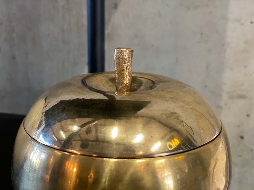 Shiny gold container with lid in the shape of an apple from the 1970s. The container is made of brass. The small hole in the bottom indicates that it was originally once the decorative cover of an ice cube cooler. However, this beautiful apple also