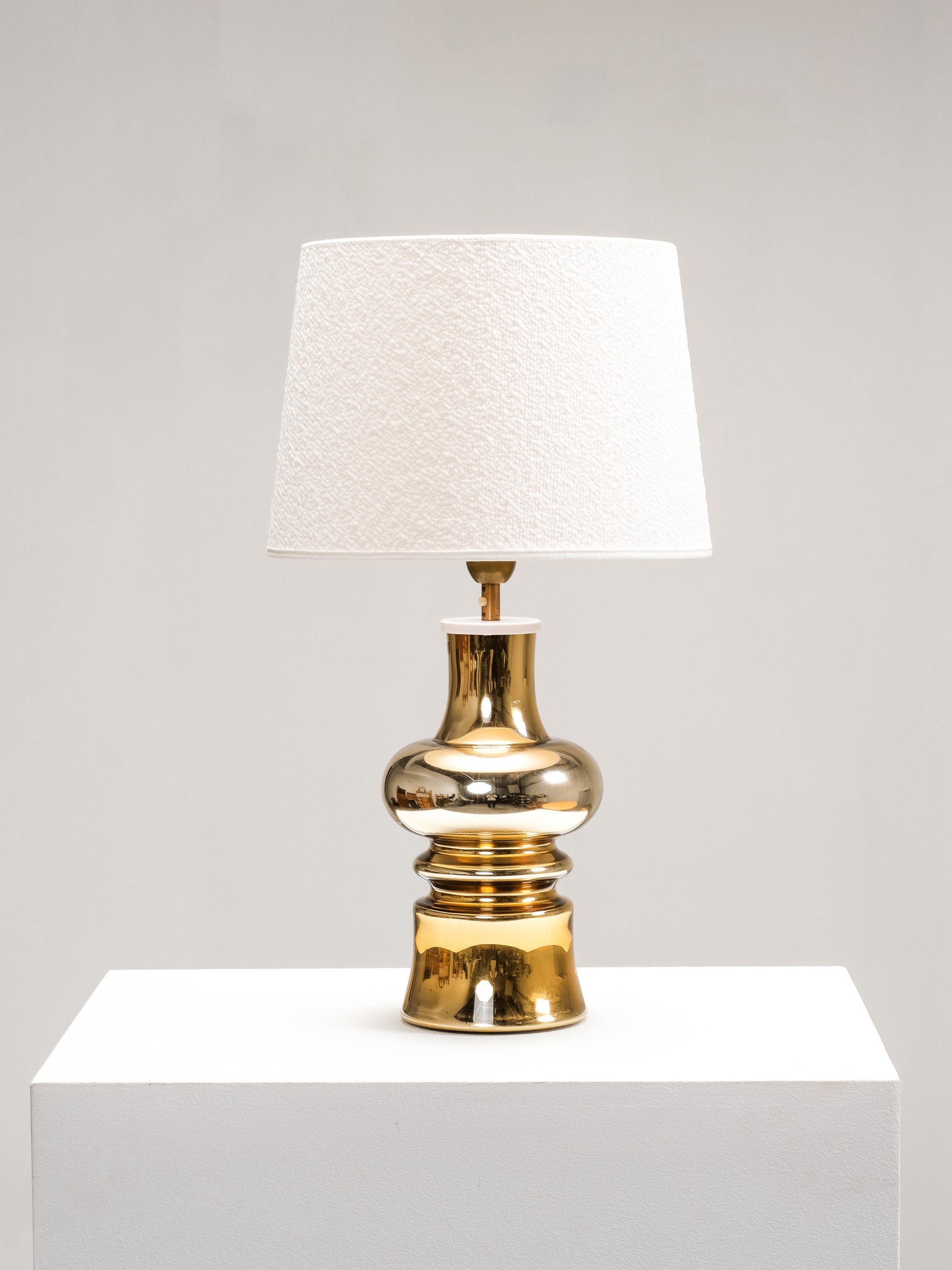 Ejemplo excepcional de la iluminación sueca de mediados de siglo, esta lámpara de sobremesa de vidrio artístico dorado fue diseñada por Gustav Leek para Flygsfors en la década de 1960. Con su silueta escultural y su acabado lustroso, la pieza