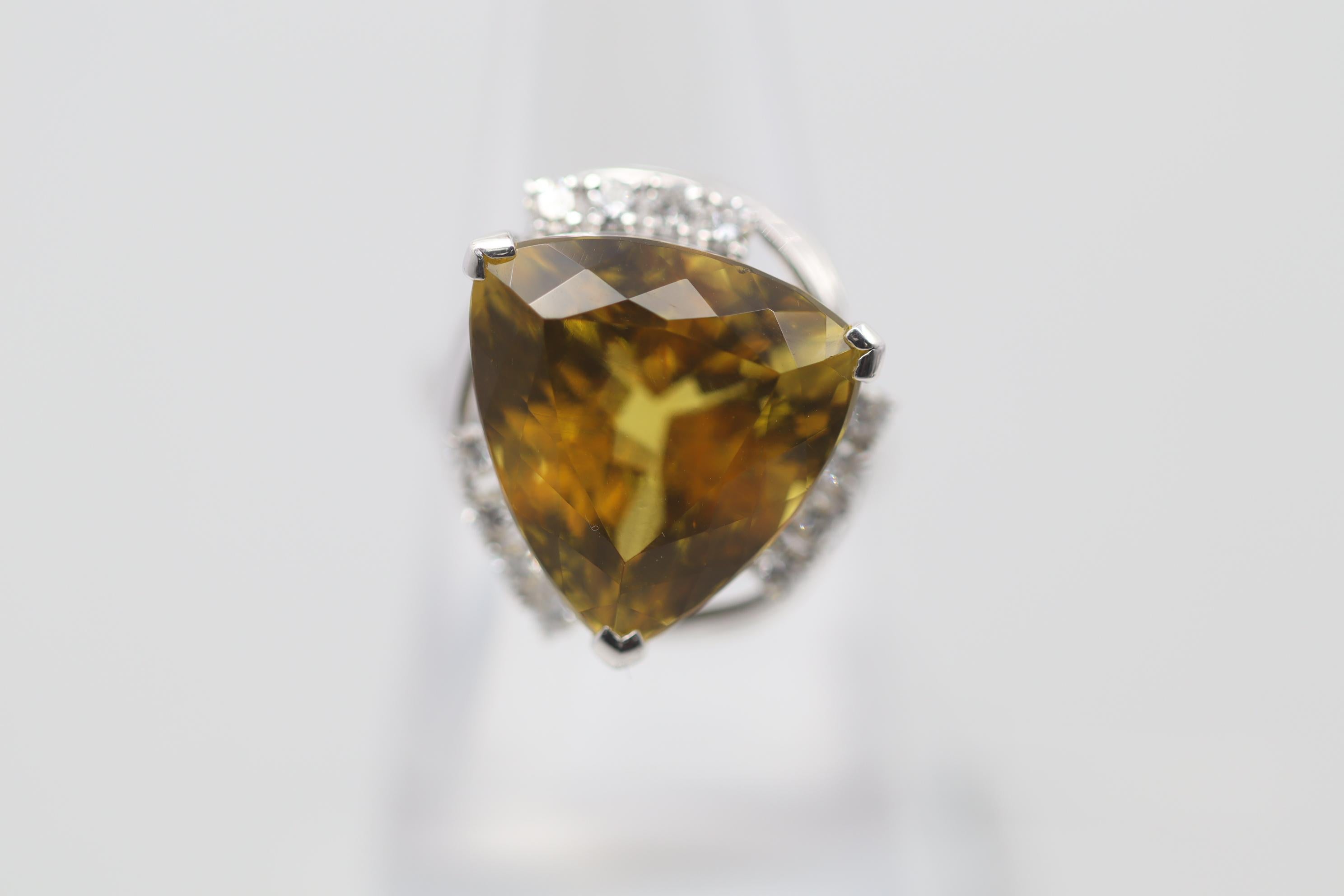 A stylish ring featuring a unique gemstone, a golden yellow beryl, which is in the same family as emerald (green beryl) and morganite (pink beryl). It weighs 14.93 carats and is shaped as a triangular brilliant-cut which gives the stone excellent