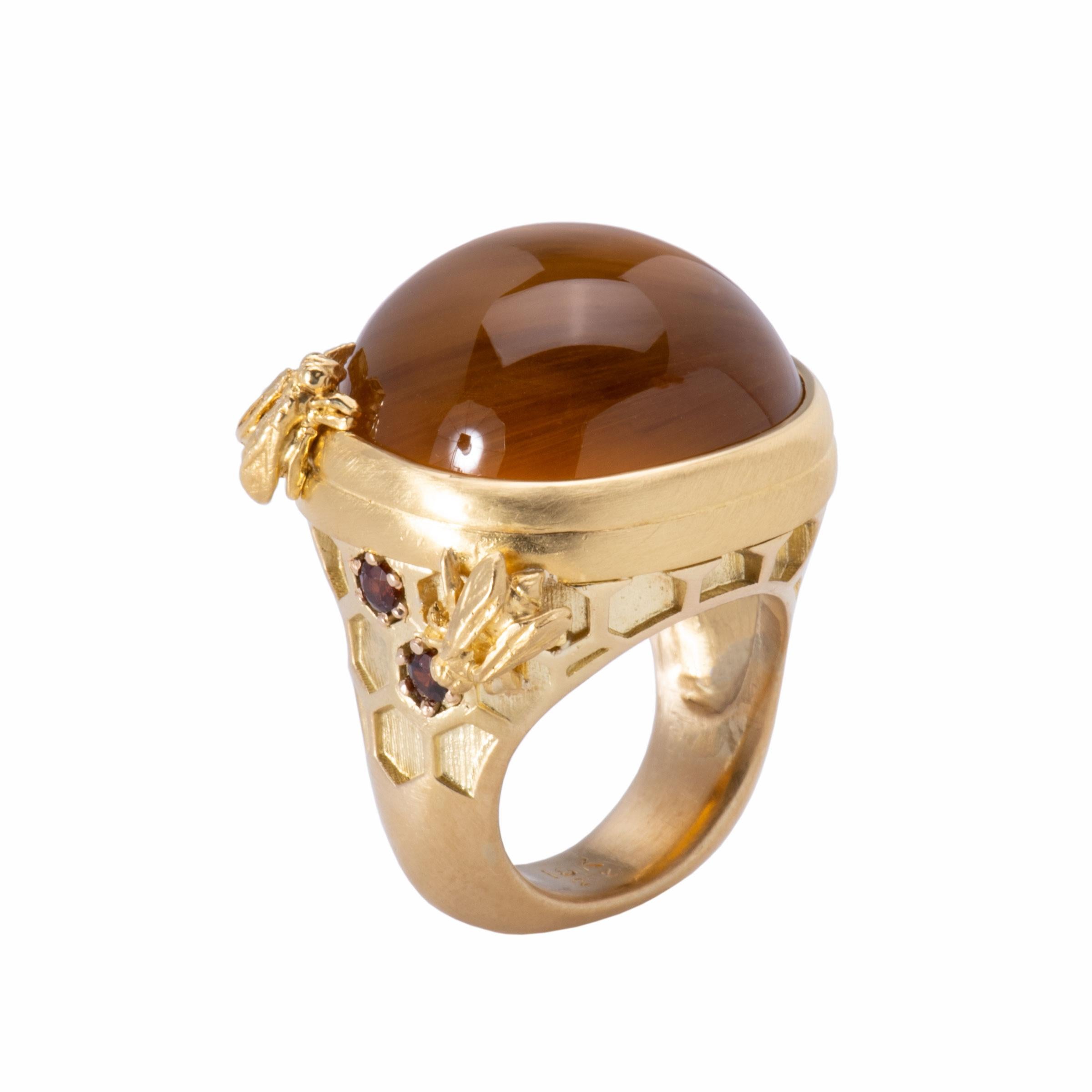 A spectacular 51.46ct honey colored golden beryl is the focus of this intricate ring. The shanks and setting are embellished with honeycomb patterns and three buzzing bees sip at the edges. Created in 22k gold and 18k gold, 2 andradite garnets