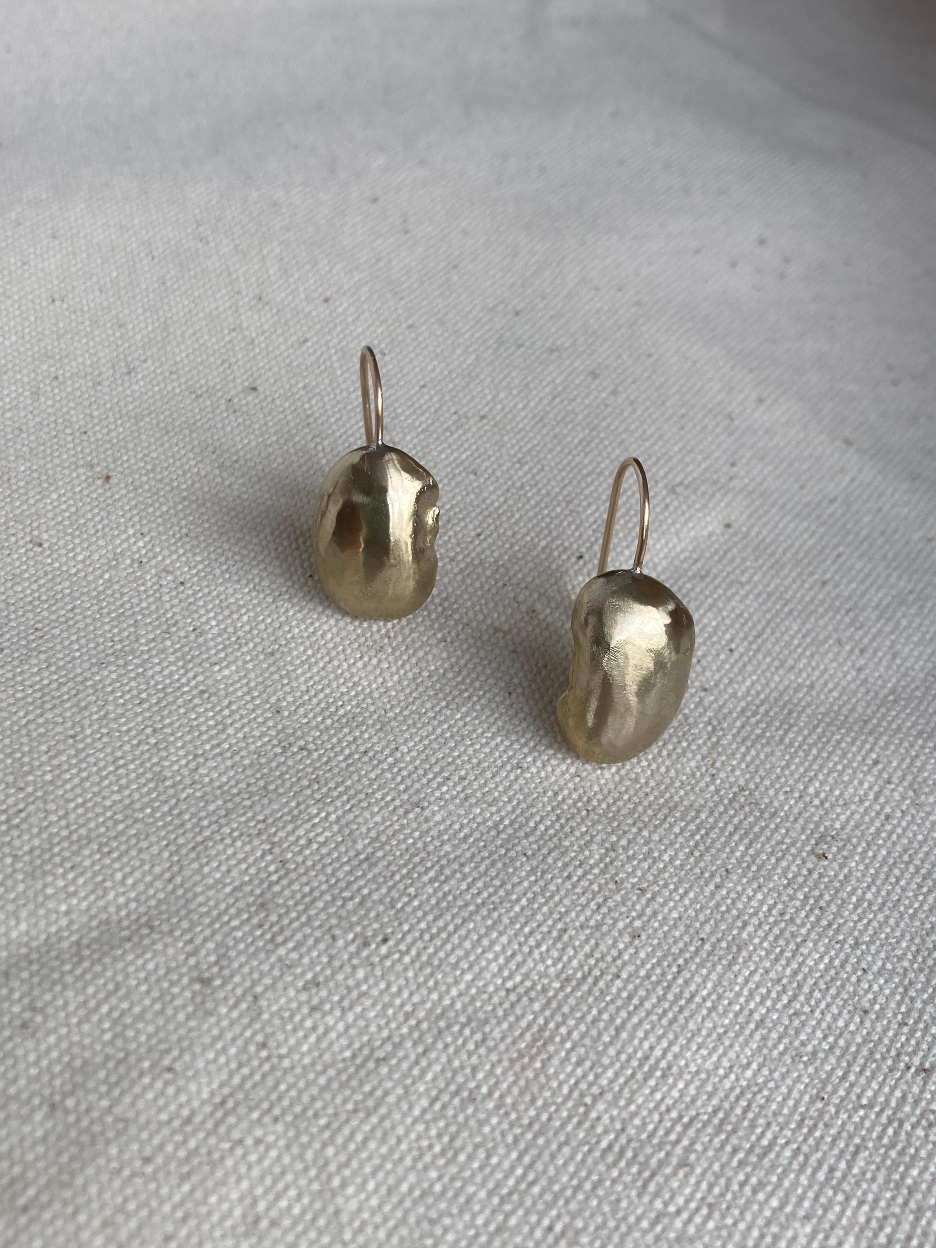 Elegant stud earrings made from Butter beans, cast in golden brass with a gold plated hook for comfortable wear.

The finished surface is naturally finished, bearing the marks of their making. 

They are secured to the ear with a classic hook.

All