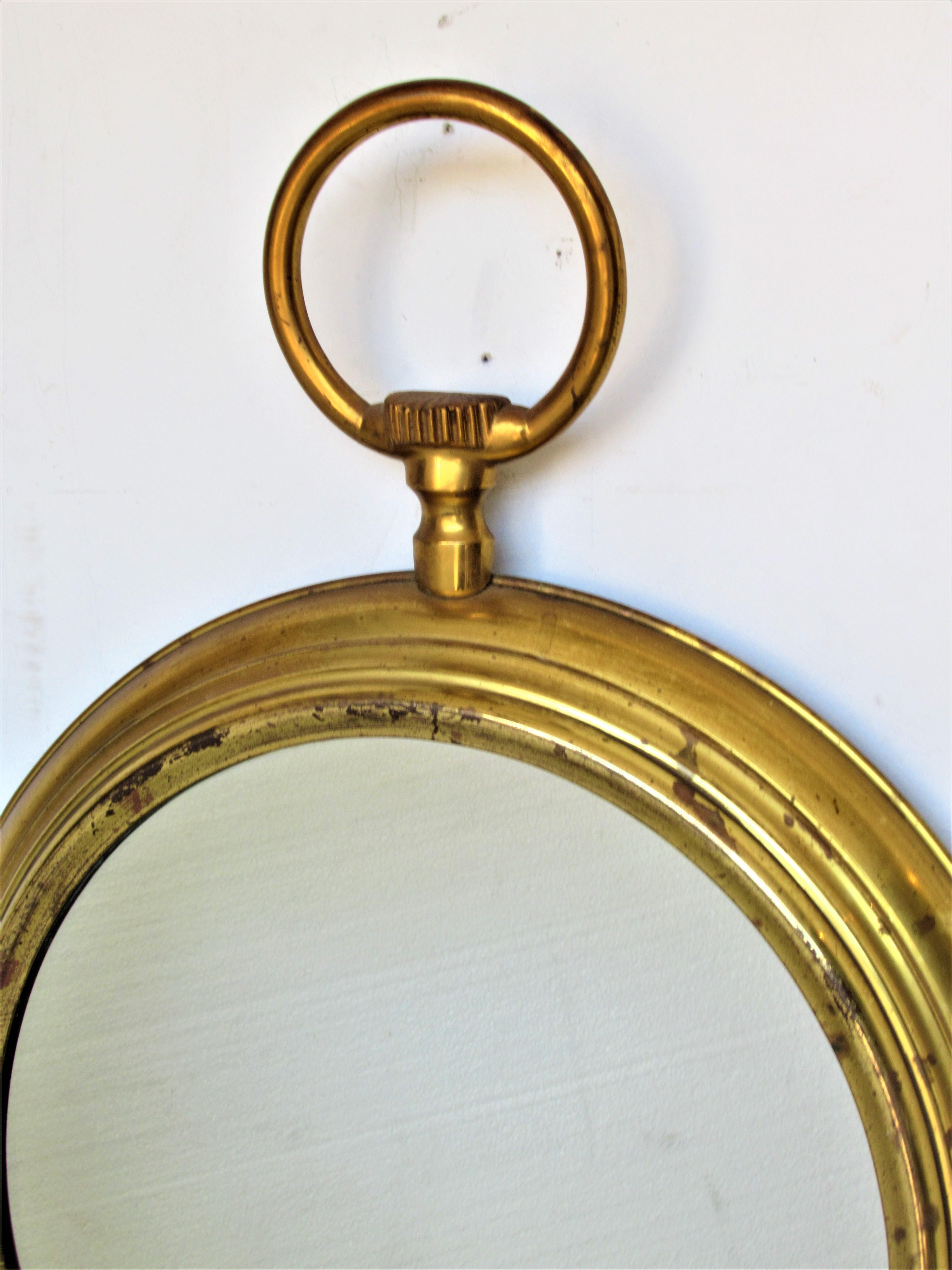 In the surrealistic style of Piero Fornasetti, Italy,  a lacquered golden brass frame wall mirror in the shape of a pocket watch. Circa 1950. Look at all pictures and read condition report in comment section.
