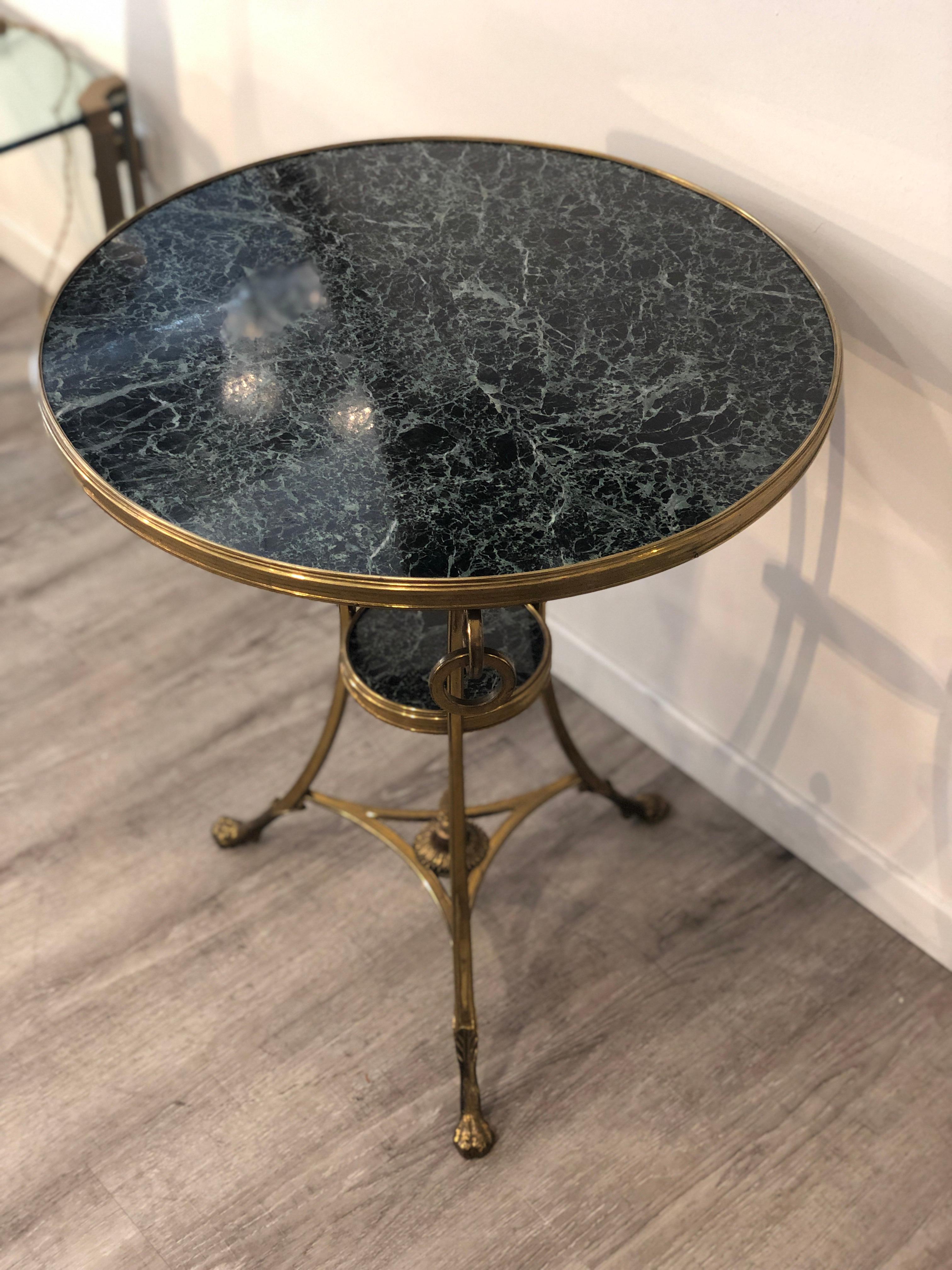 Brass and green alps marble rounded gueridon small table from France from mid century. Empire style and details such as pine cones and lion ending legs.
It features three bronze rings hang on the top where the legs end. This table features two tops