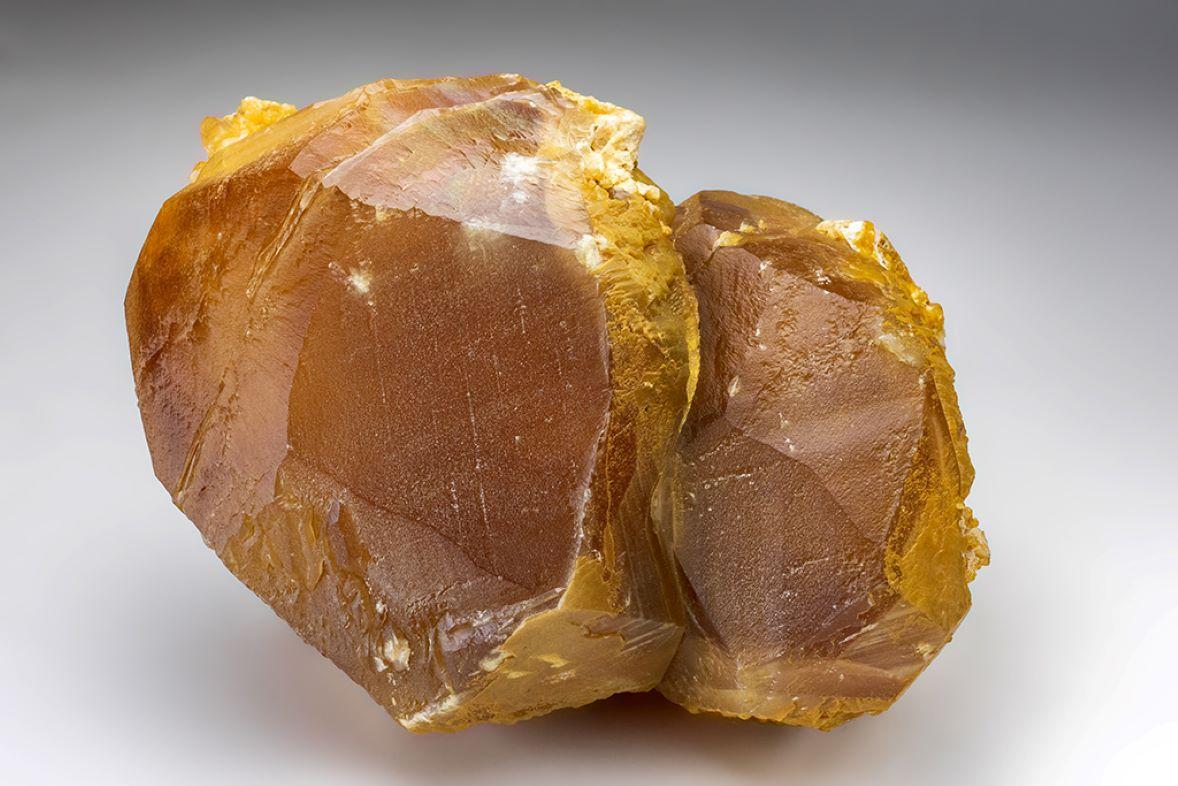 Macizos cristales romboédricos maclados de calcita con un intenso color entre naranja y amarillo en toda su superficie. Totalmente terminados con caras de cristales lustrosos con ligeras estrías y  iridiscencia arco iris en algunas zonas.

 

22