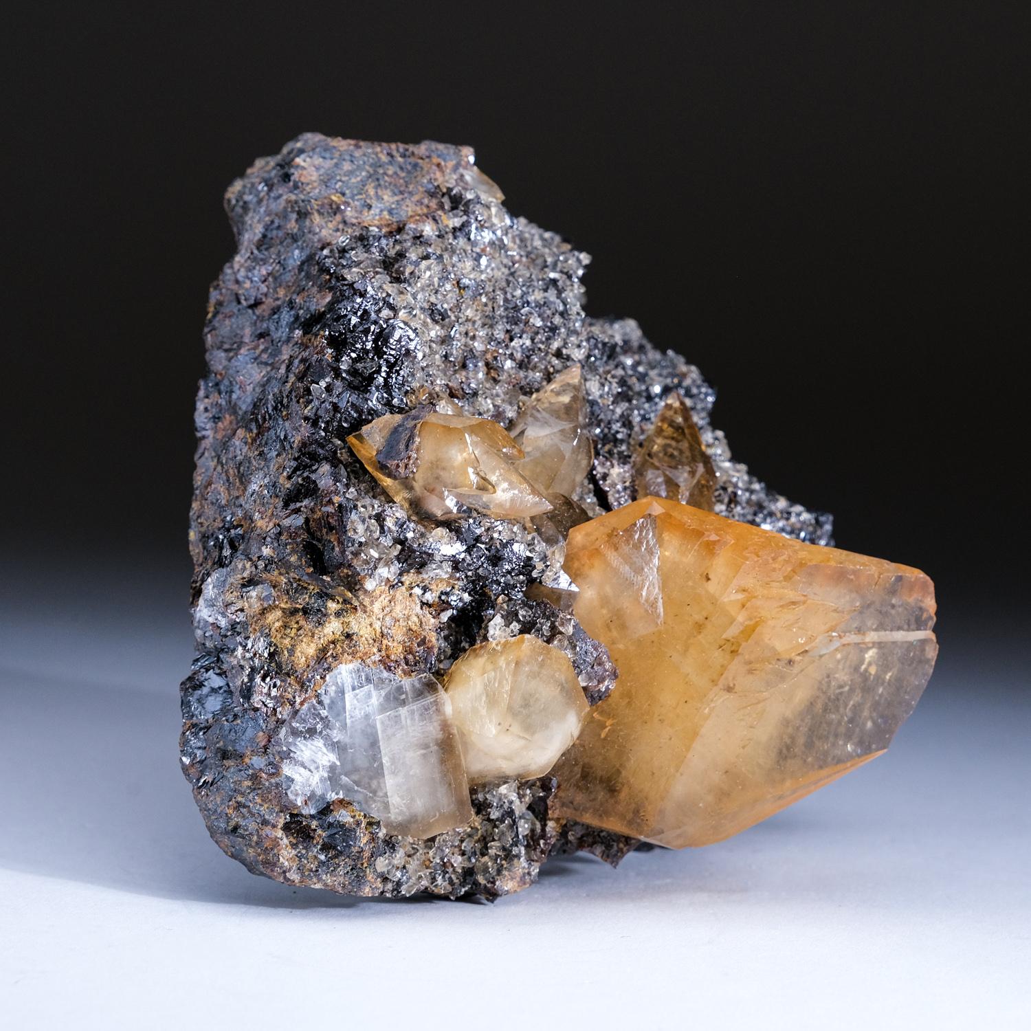 Large, museum-quality, lustrous transparent deep golden calcite with sphalerite crystal at the base of the crystal. Double terminated scalenohedral twinned on the C-axis with well defined re-entrant faces, and crystal faces exhibiting subparallel