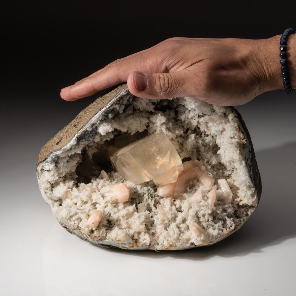 From Nasik District, Maharashtra, India

Large geode with a transparent penetrating twinned golden calcite on druzy chalcedony matrix in stalactitic formations with several isolated pink stilbite crystals. The calcite show sharp rhombic form with a