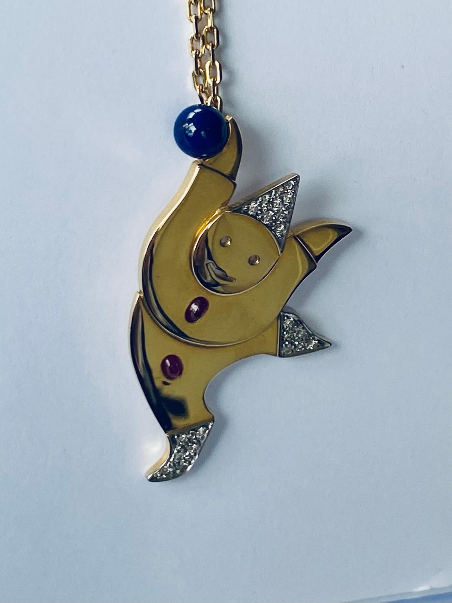 One (1) 18K. Yellow and White Gold Pendant with Chain, stamped 750
set with:
21 round brillant cut natural diamonds, 2 oval cabuchon natural Rubies and 1 Lapis Lazuli  Ball.
Hand made  (one of a kind)
Total weight: 20.92 cm.
lenght of the 18K.