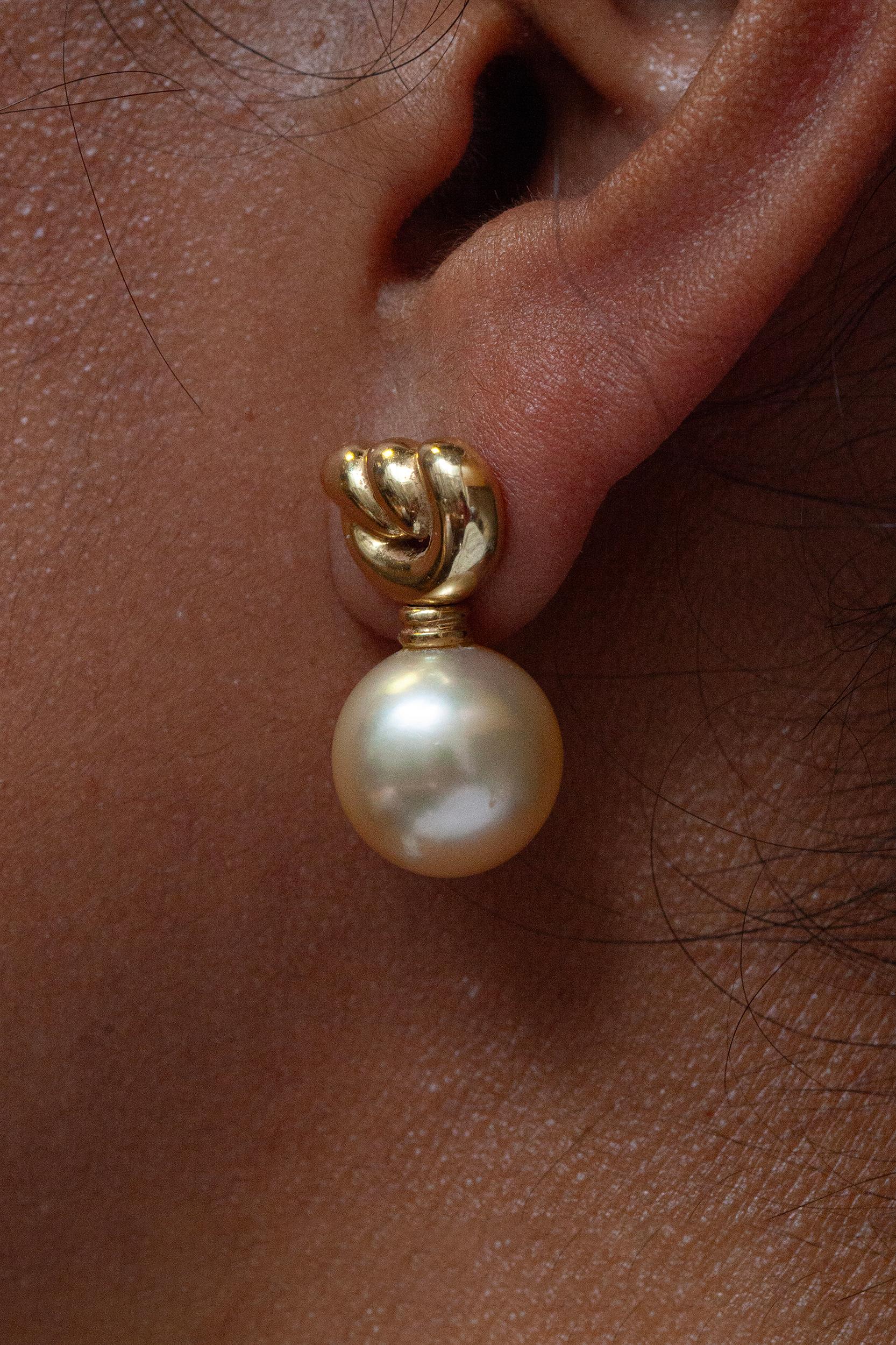 Experience timeless elegance with these delicate and elegant love knot dangle earrings. 

Each earring features a lustrous  14mm golden cultured pearl, that suspends gracefully from an intricately designed 18 carat yellow gold knot stud. The