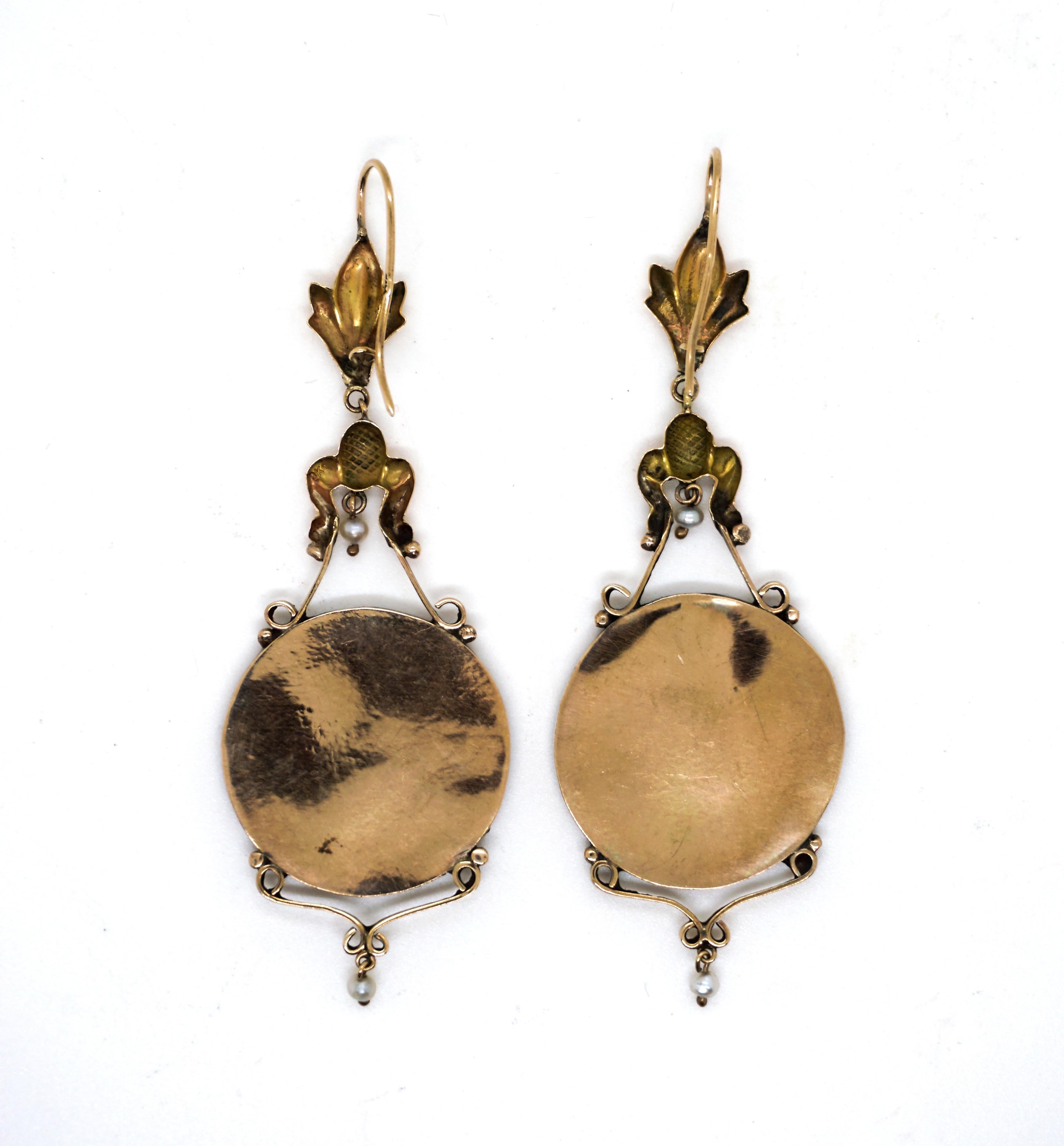 Pair of delicate rose gold earrings with movable drop-shaped pendant, decorated with stylized flowers and leaves, as well as movably suspended seed pearls, medallion with enamel painted motif, probably Italian

Made circa 1890

Dimensions:
total