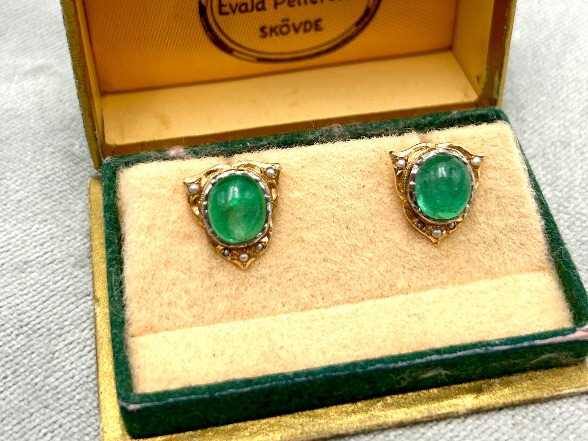 Gold earrings with emeralds and pearls. Made of 0.750 yellow gold and 2 oval cabochon-cut emeralds of a total weight of approx. 3.2 ct; surrounded by 10 natural small pearls. The earrings have an old-style clasp for tightening to the earlobe.